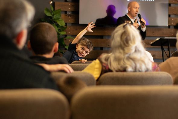 A group of people are sitting under a tent talking to each other.