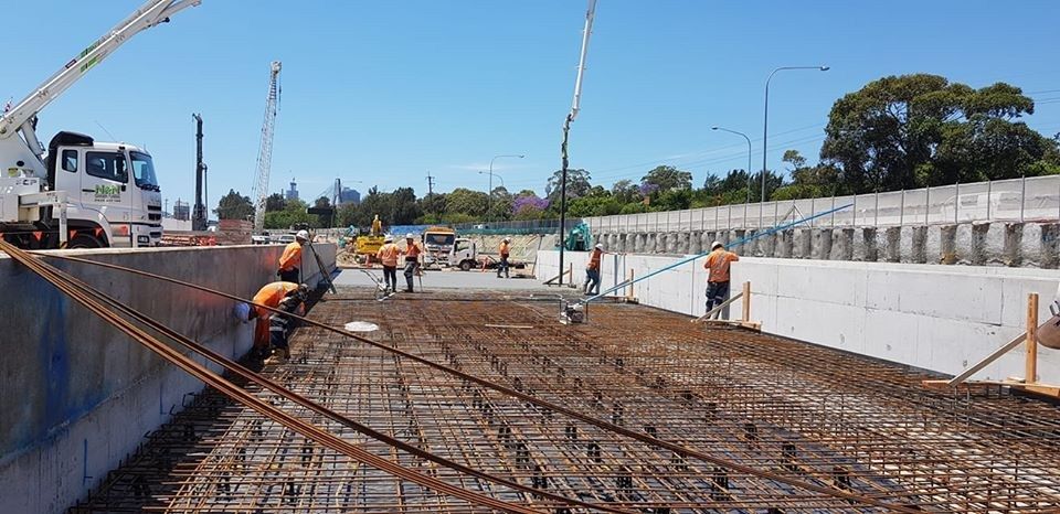 White concrete pump truck at a construction site near buildings.