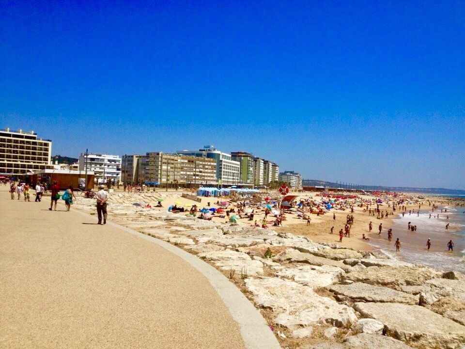 A beach with a lot of people and buildings in the background