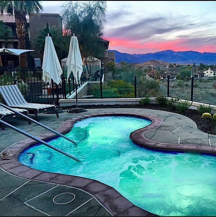 A large swimming pool surrounded by chairs and umbrellas