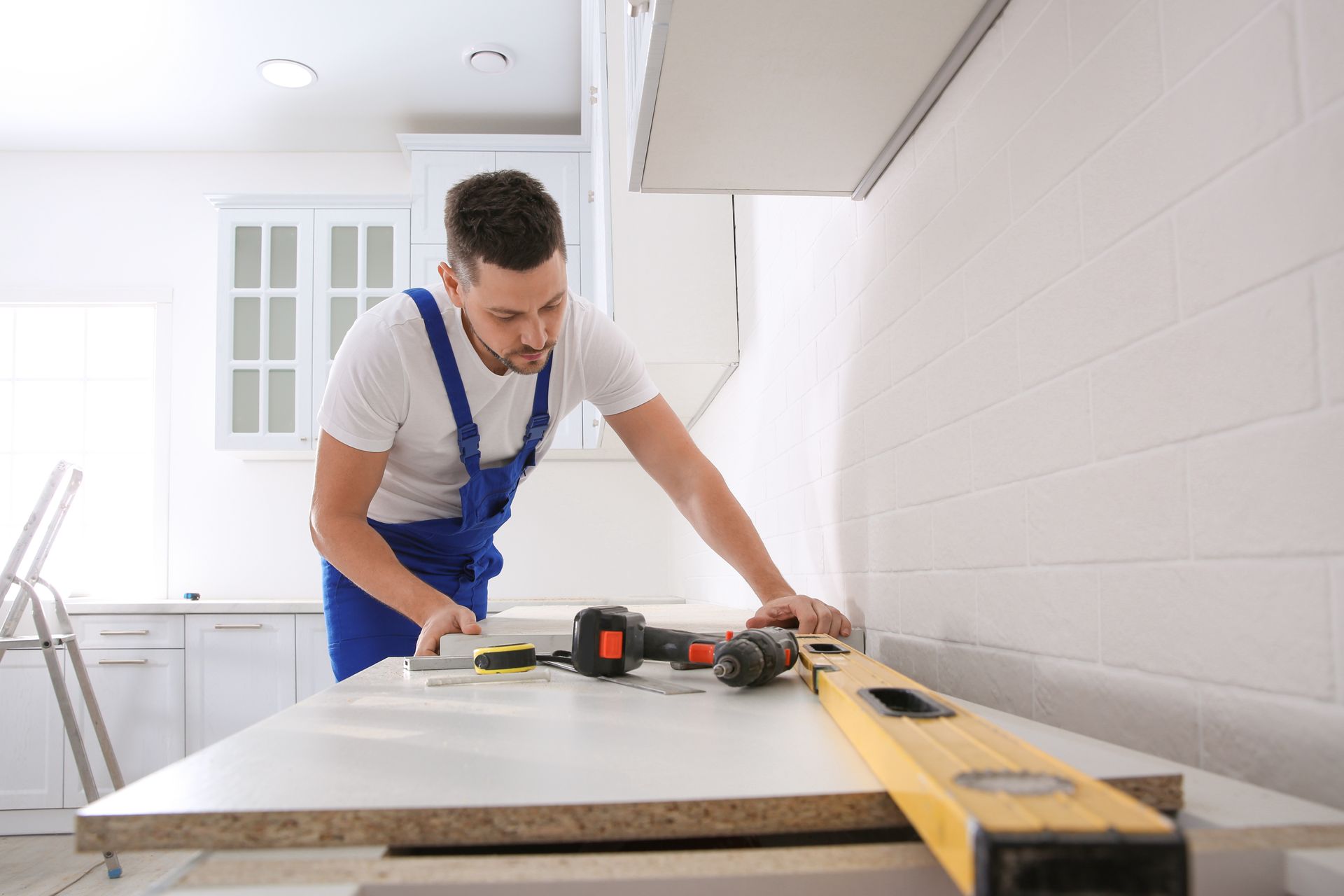 A man is using a level to measure a piece of wood in a kitchen.