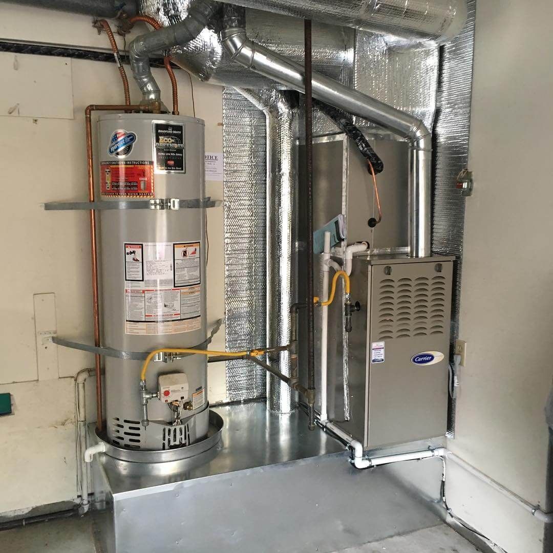 A water heater is sitting in a room next to a furnace.