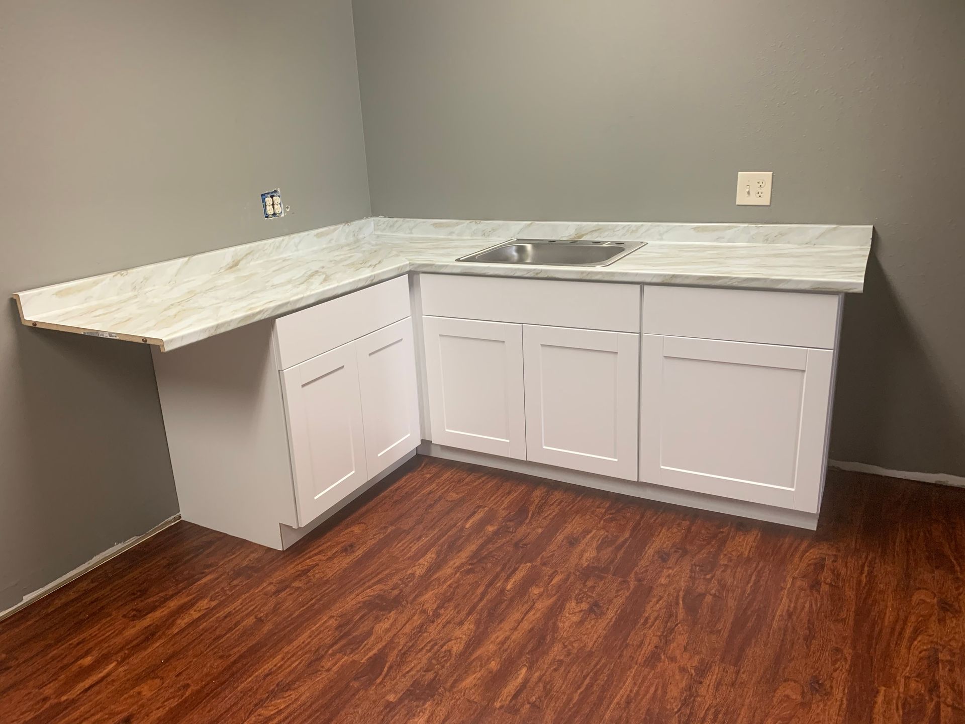 A kitchen with a sink , cabinets , and hardwood floors.