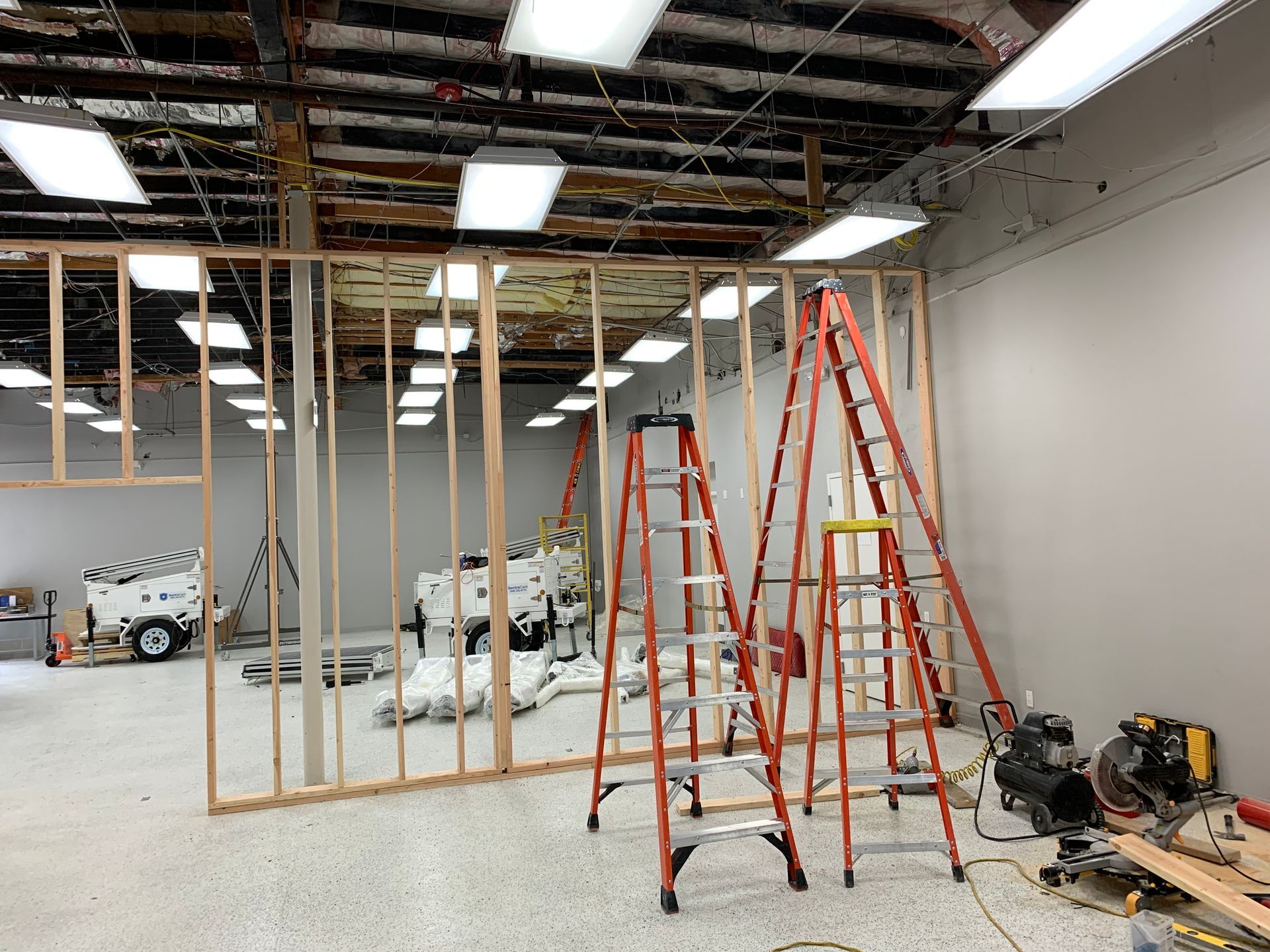 Two ladders are sitting in a room under construction.