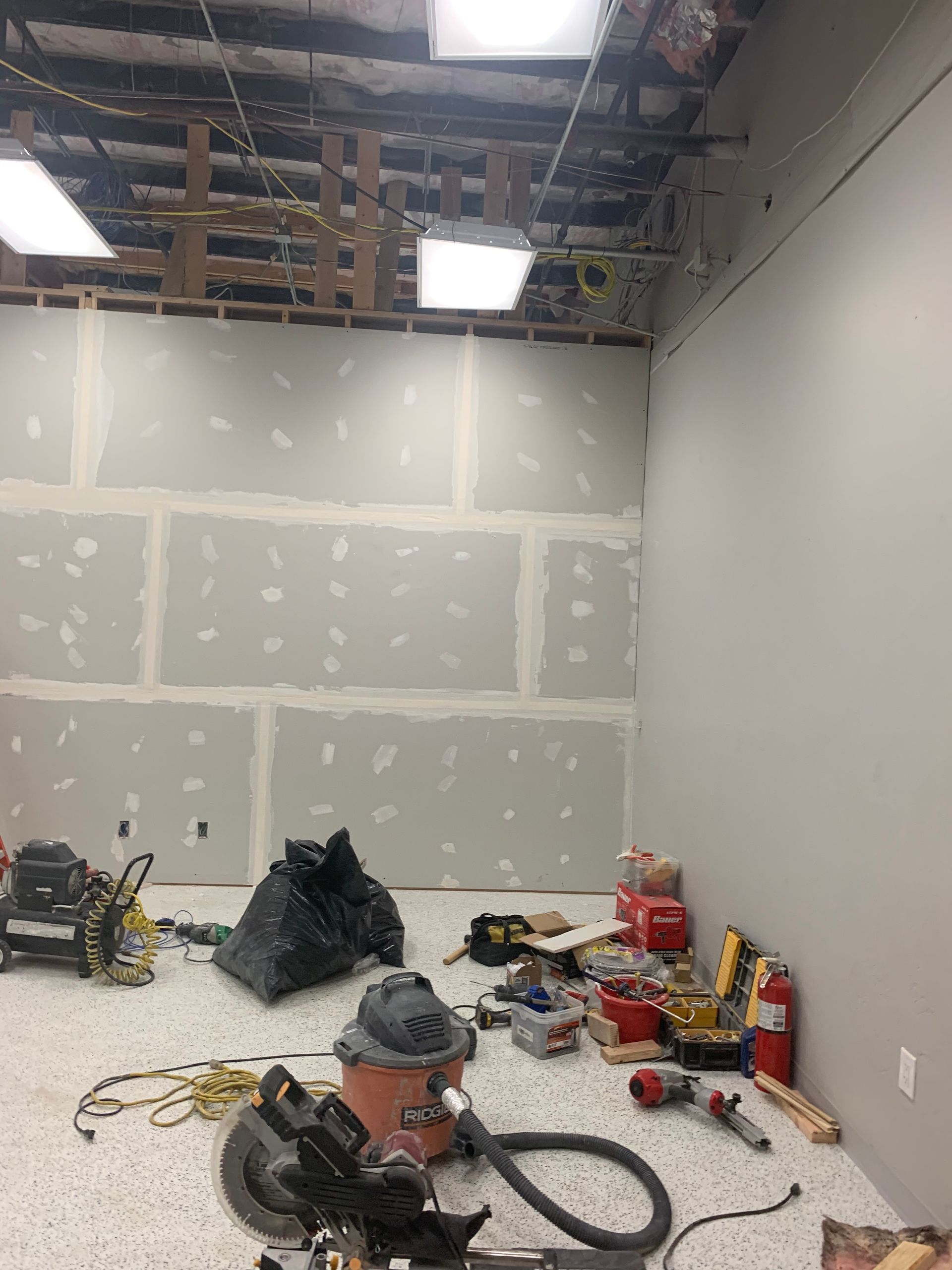 A room with a vacuum cleaner and tools on the floor.