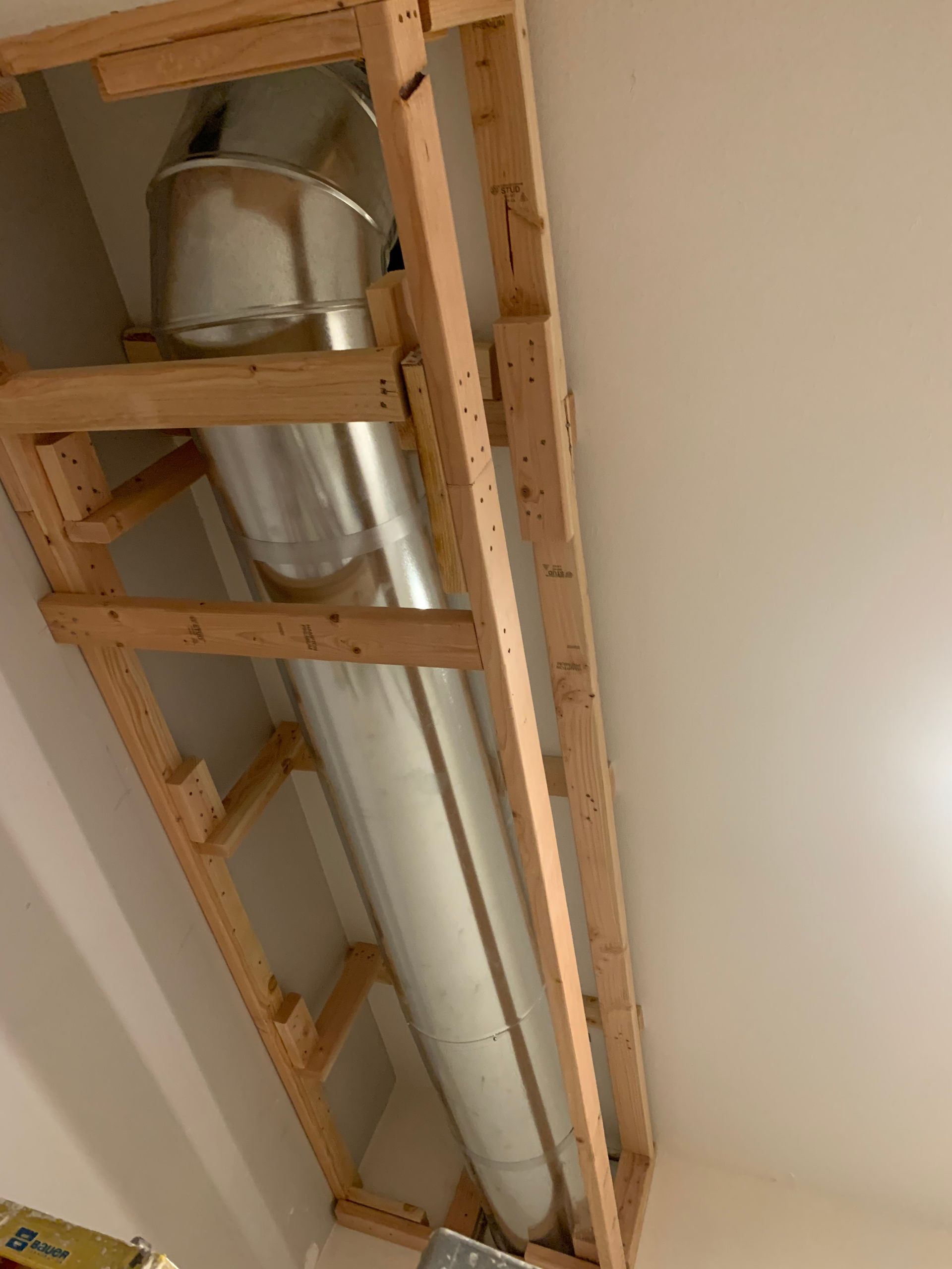 A large metal pipe is hanging from the ceiling in a wooden frame.