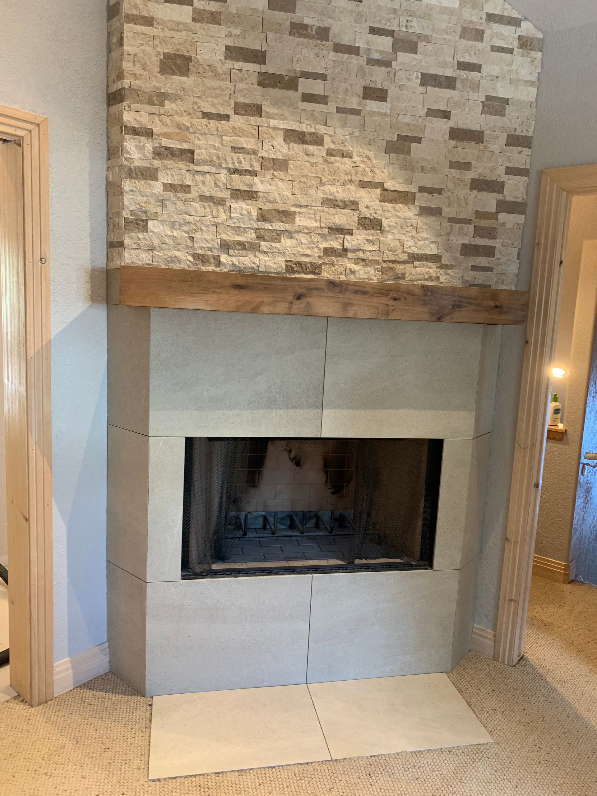 A fireplace in a room with a brick wall and a wooden mantle.