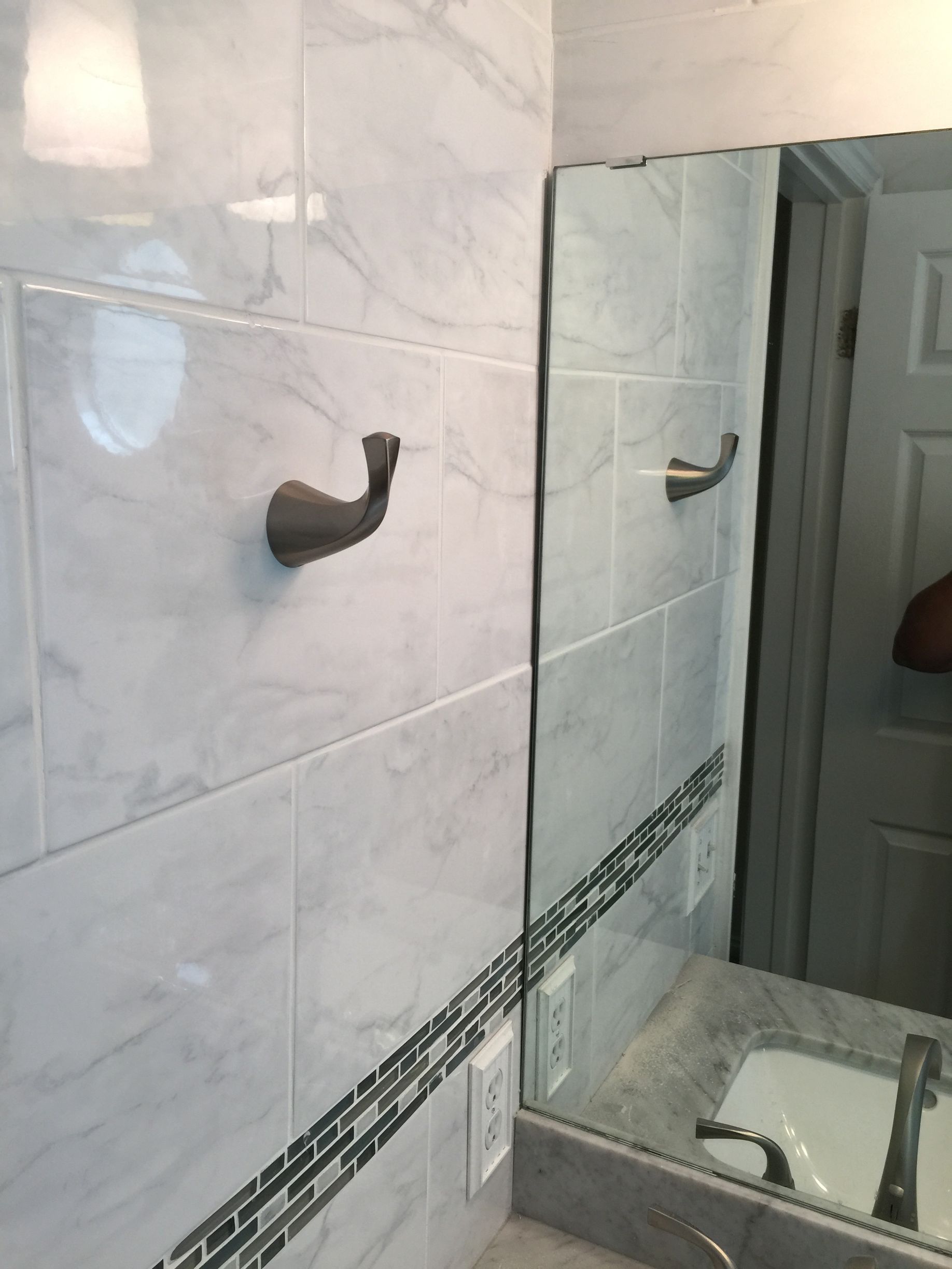 A bathroom with white tiles and a large mirror