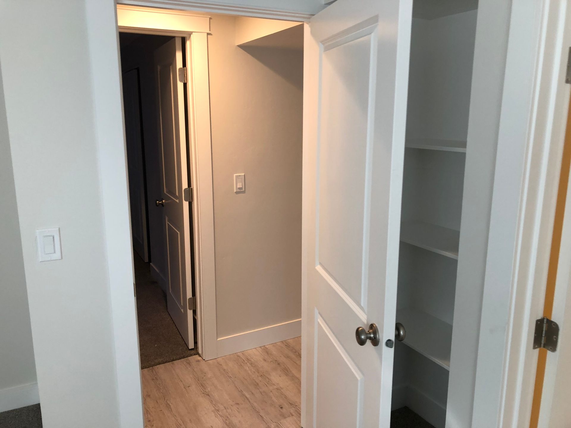 A hallway in a house with a closet and a door open.