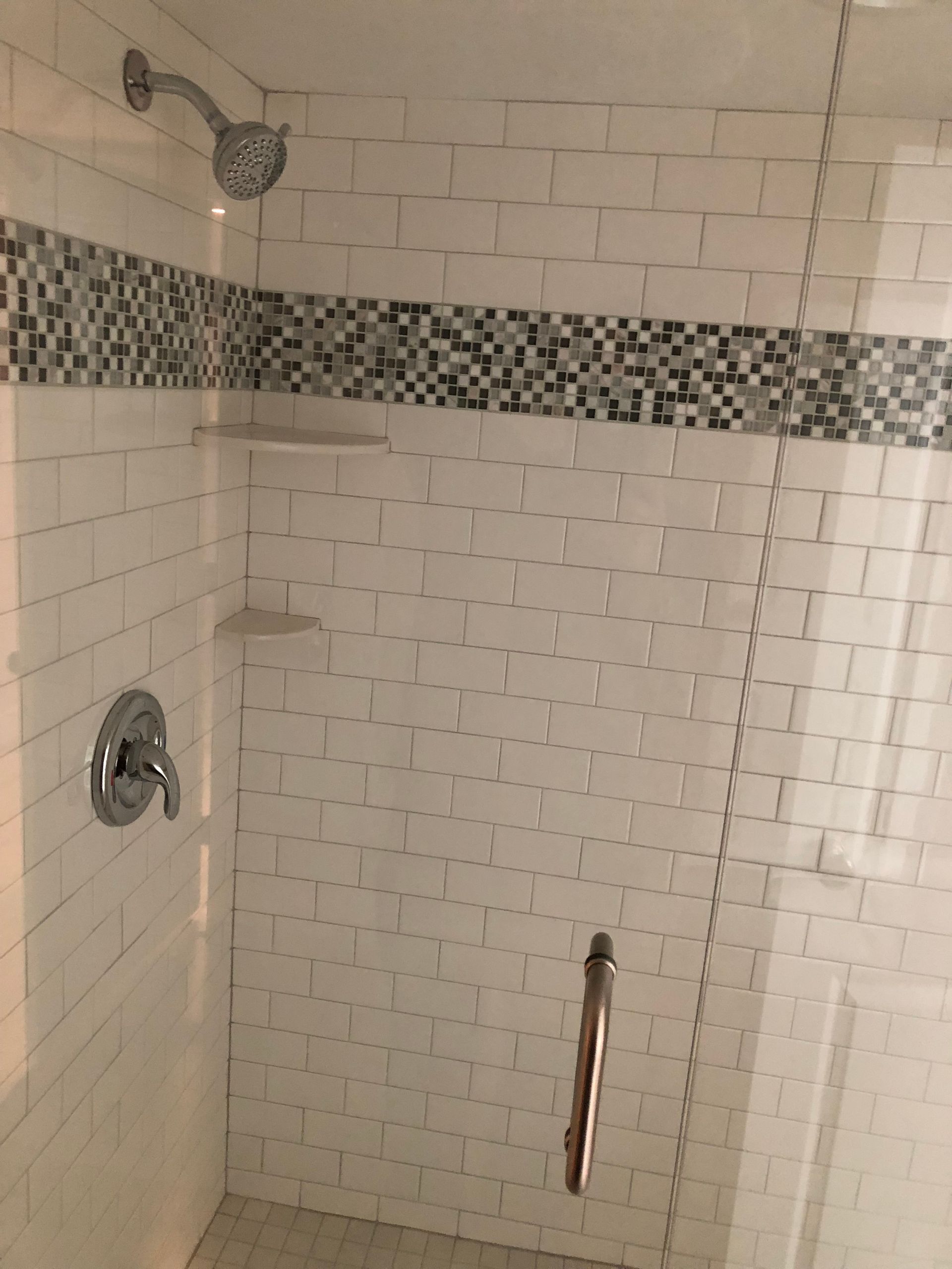 A shower with a glass door and a shower head on the wall.