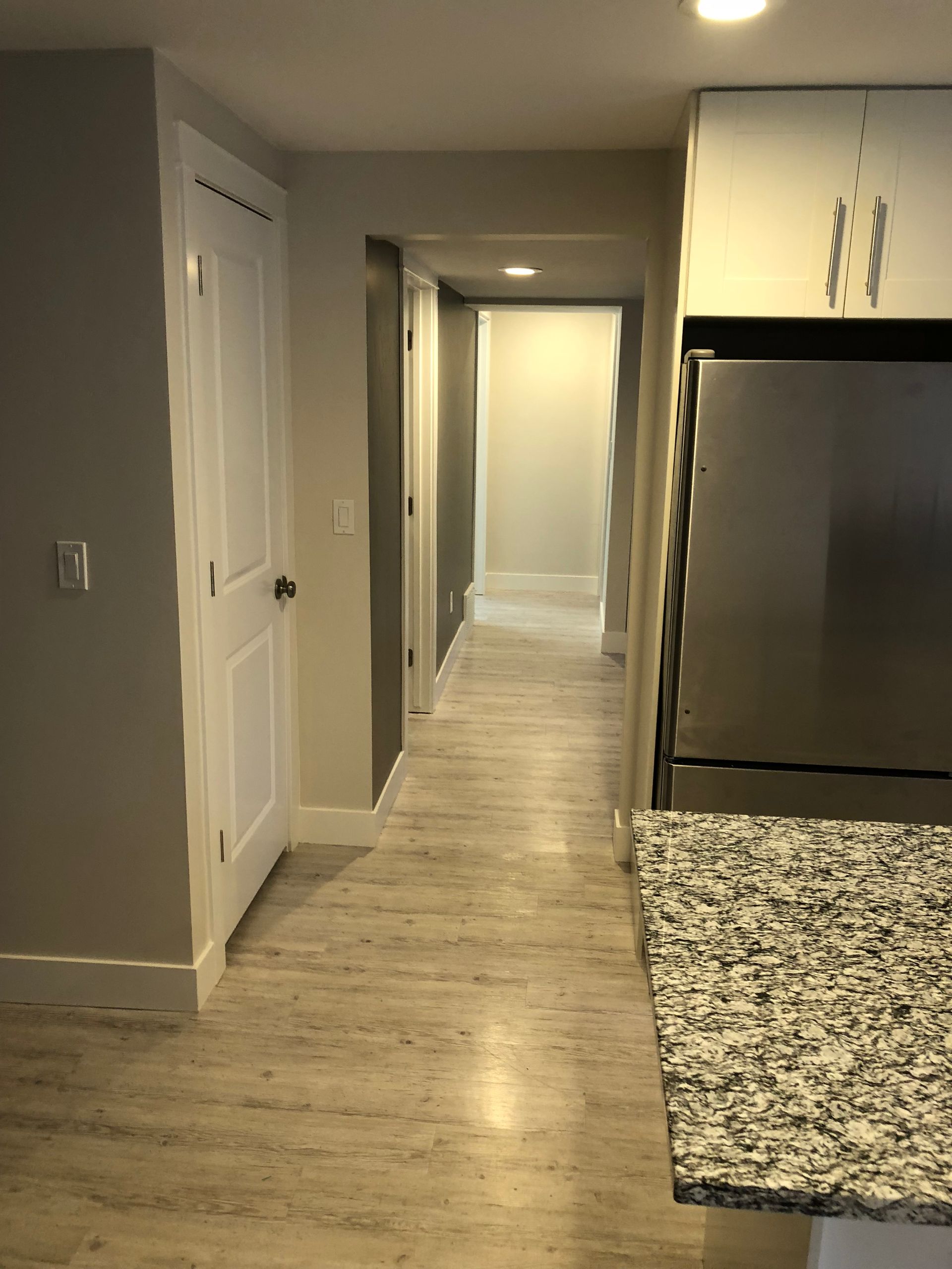 A hallway in a house with a stainless steel refrigerator