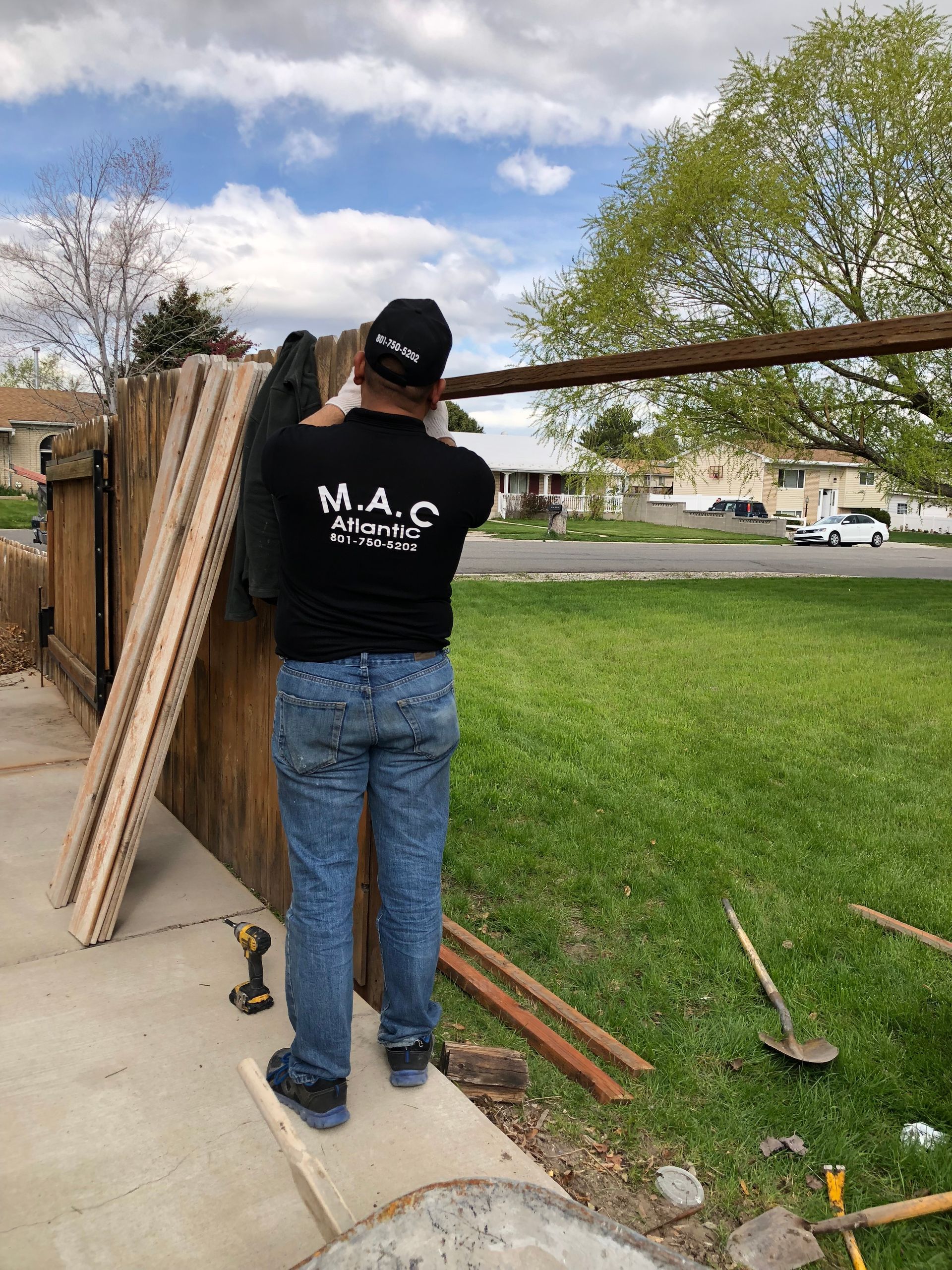 A man in a black shirt is standing next to a wooden fence.
