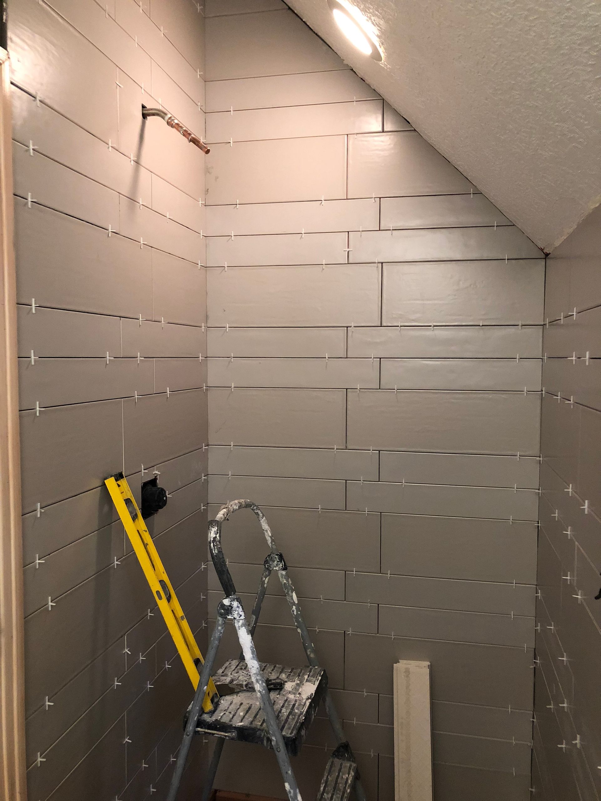 A ladder is leaning against a wall next to a yellow level.