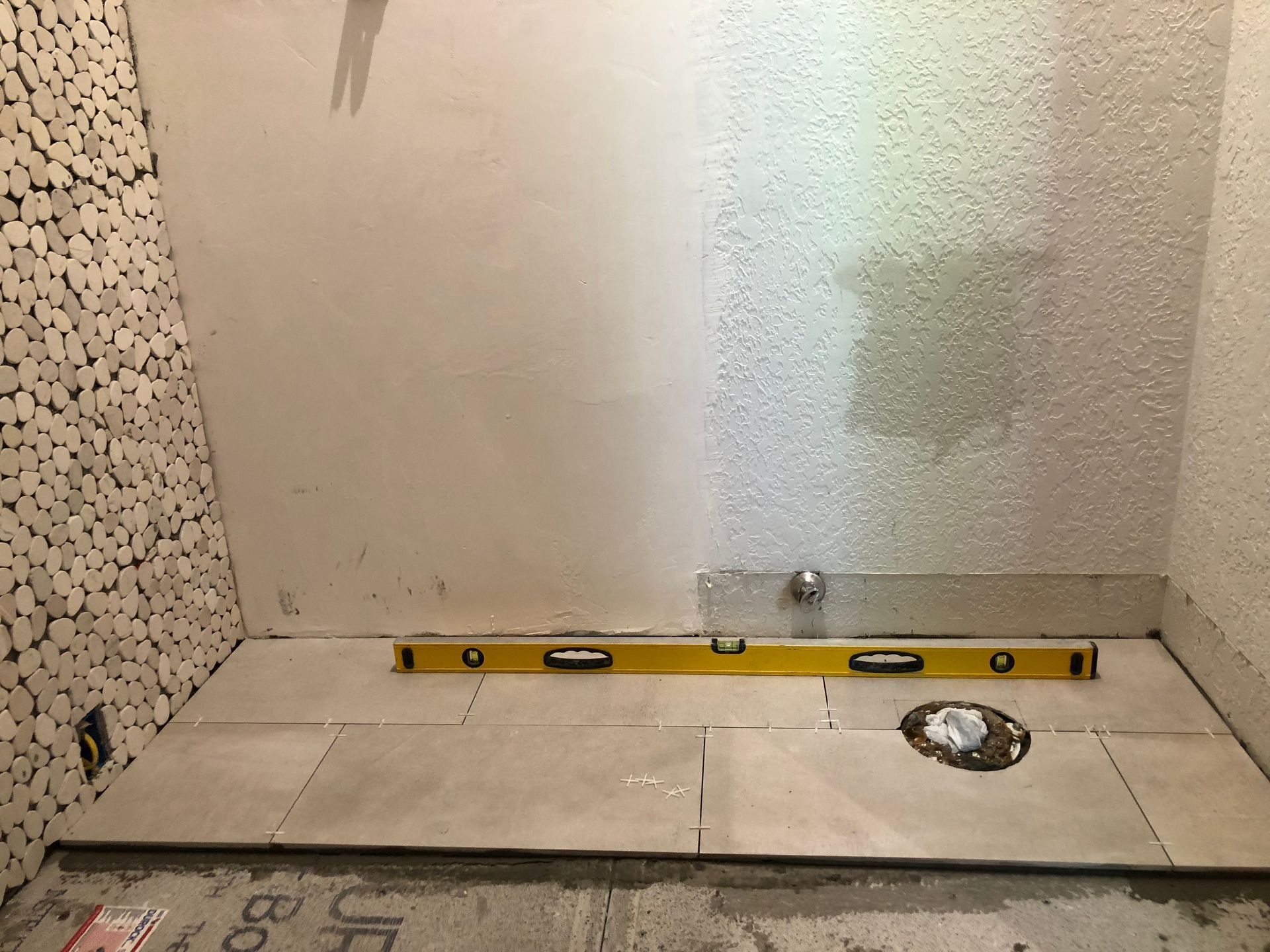 A yellow level is sitting on a tiled floor in a bathroom.