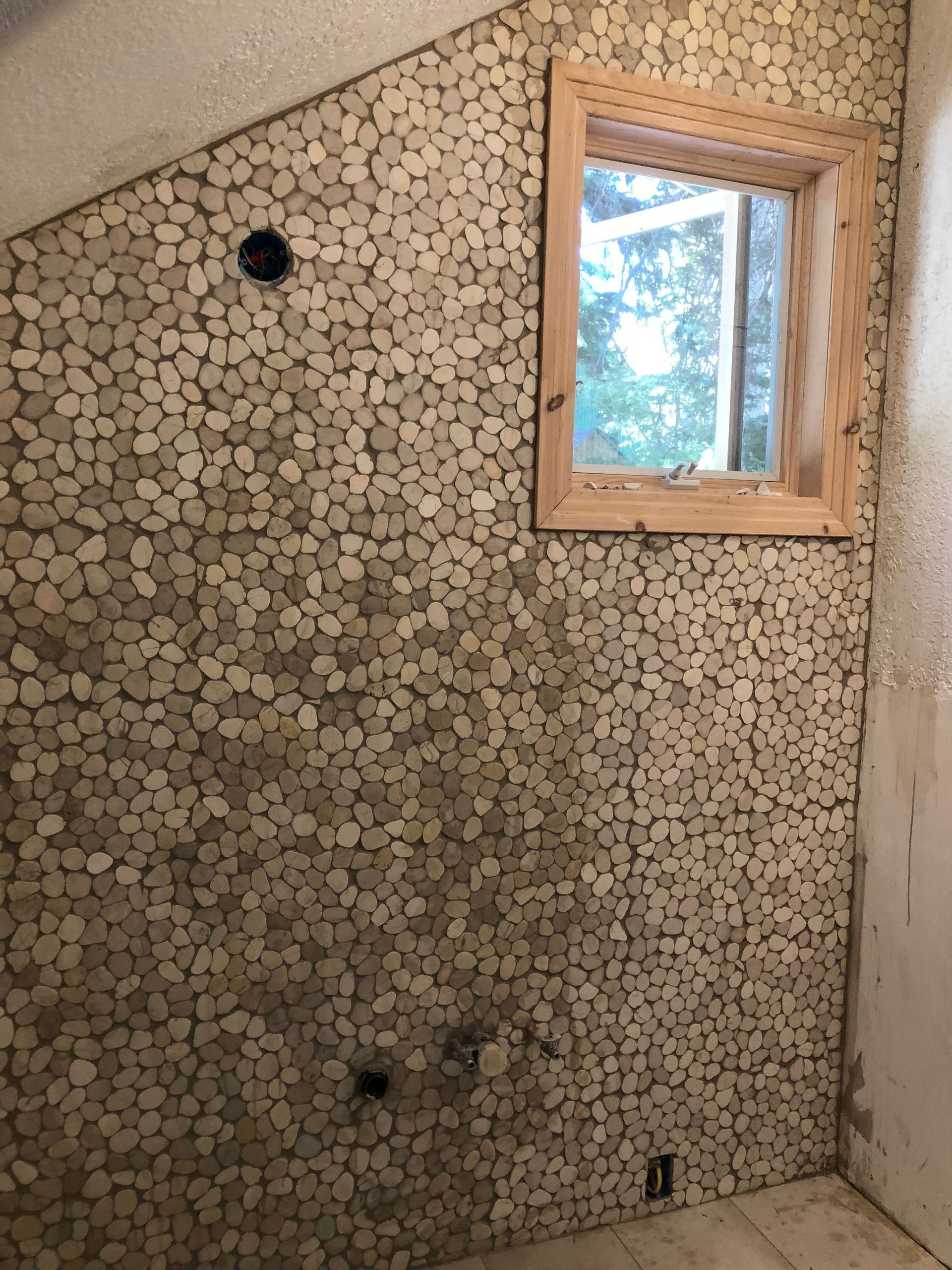 A bathroom with a tiled wall and a window