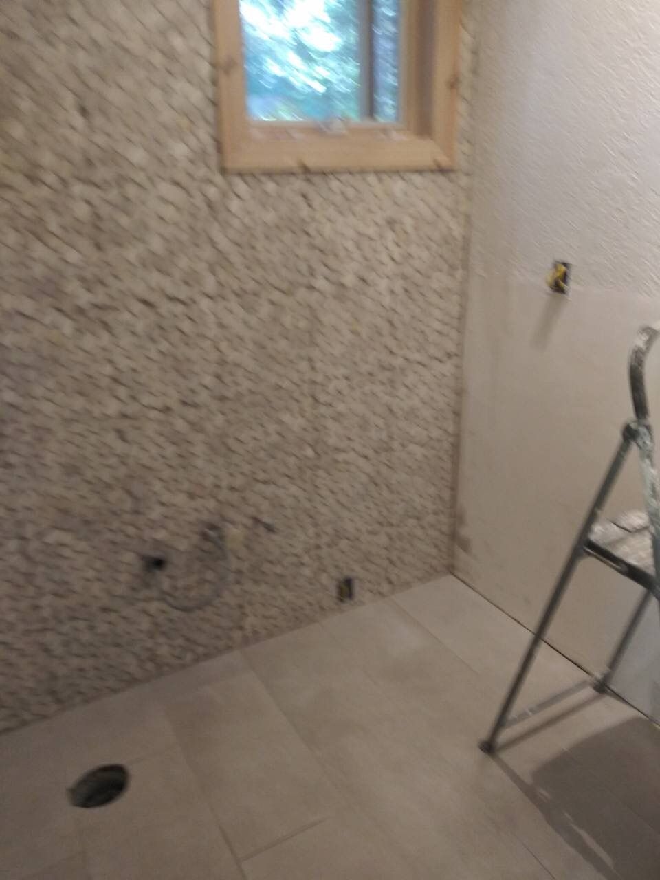 A bathroom with a window and a ladder in it.