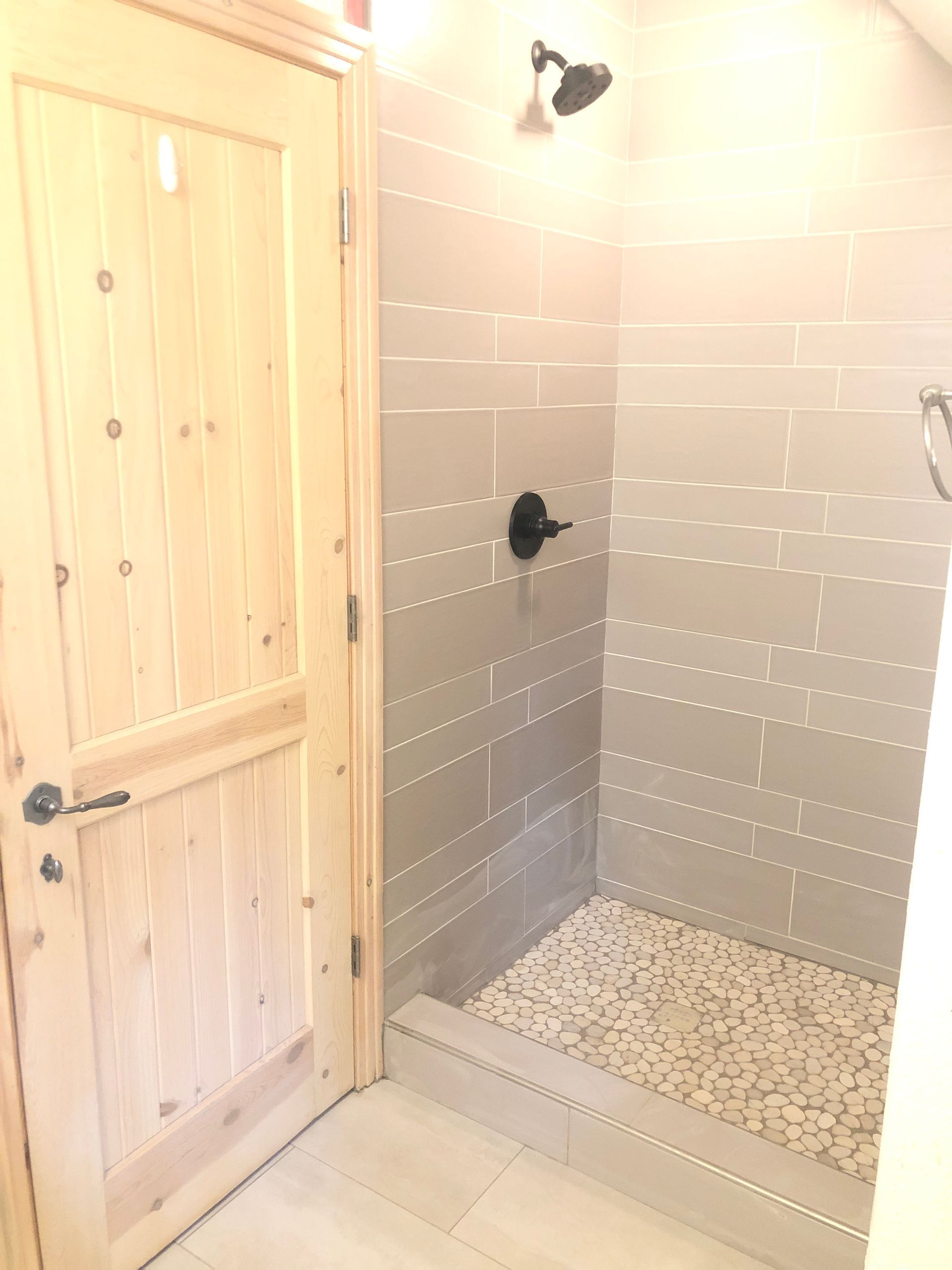 A bathroom with a walk in shower and a wooden door.