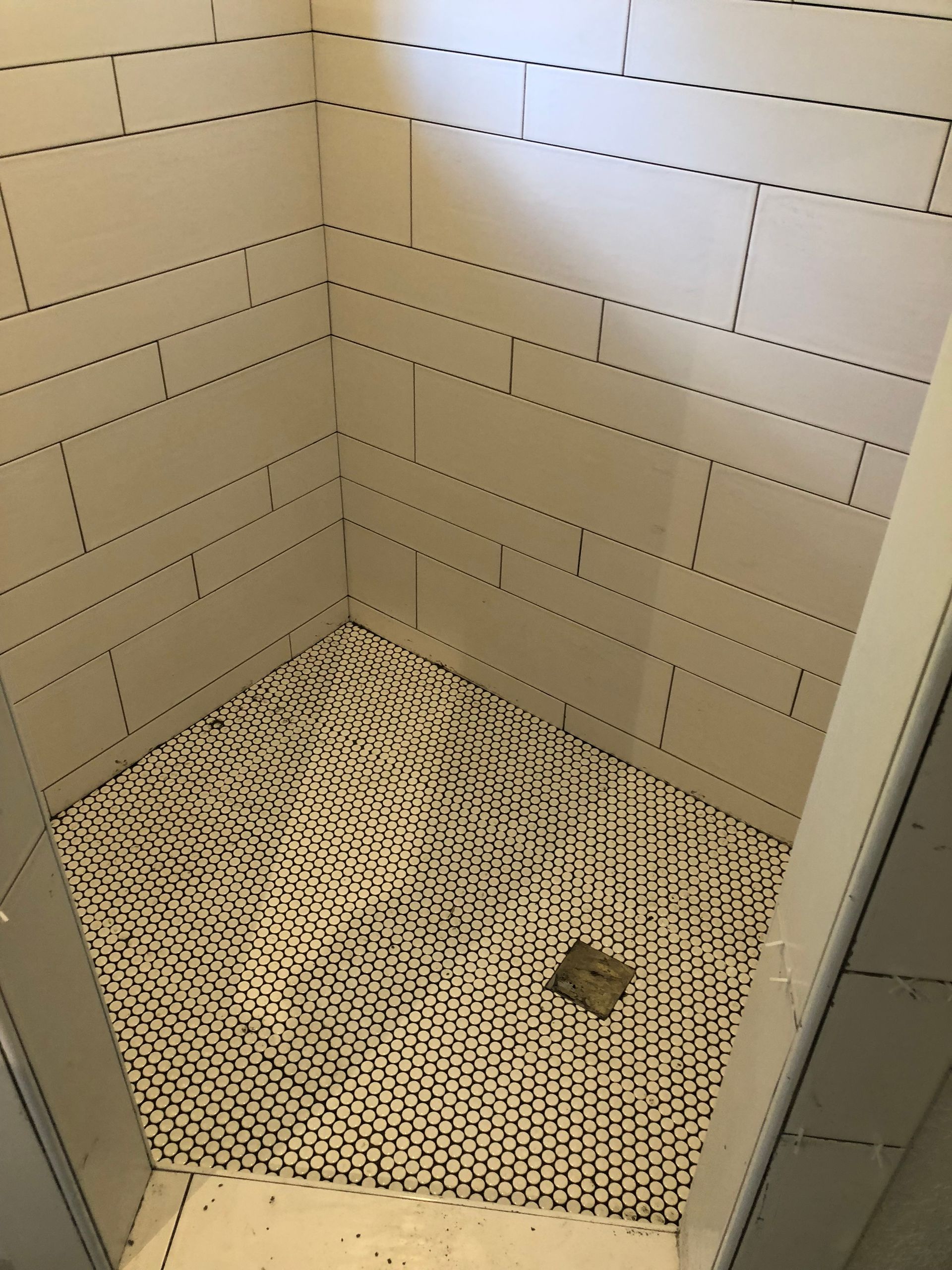 A shower stall with a black and white tile floor