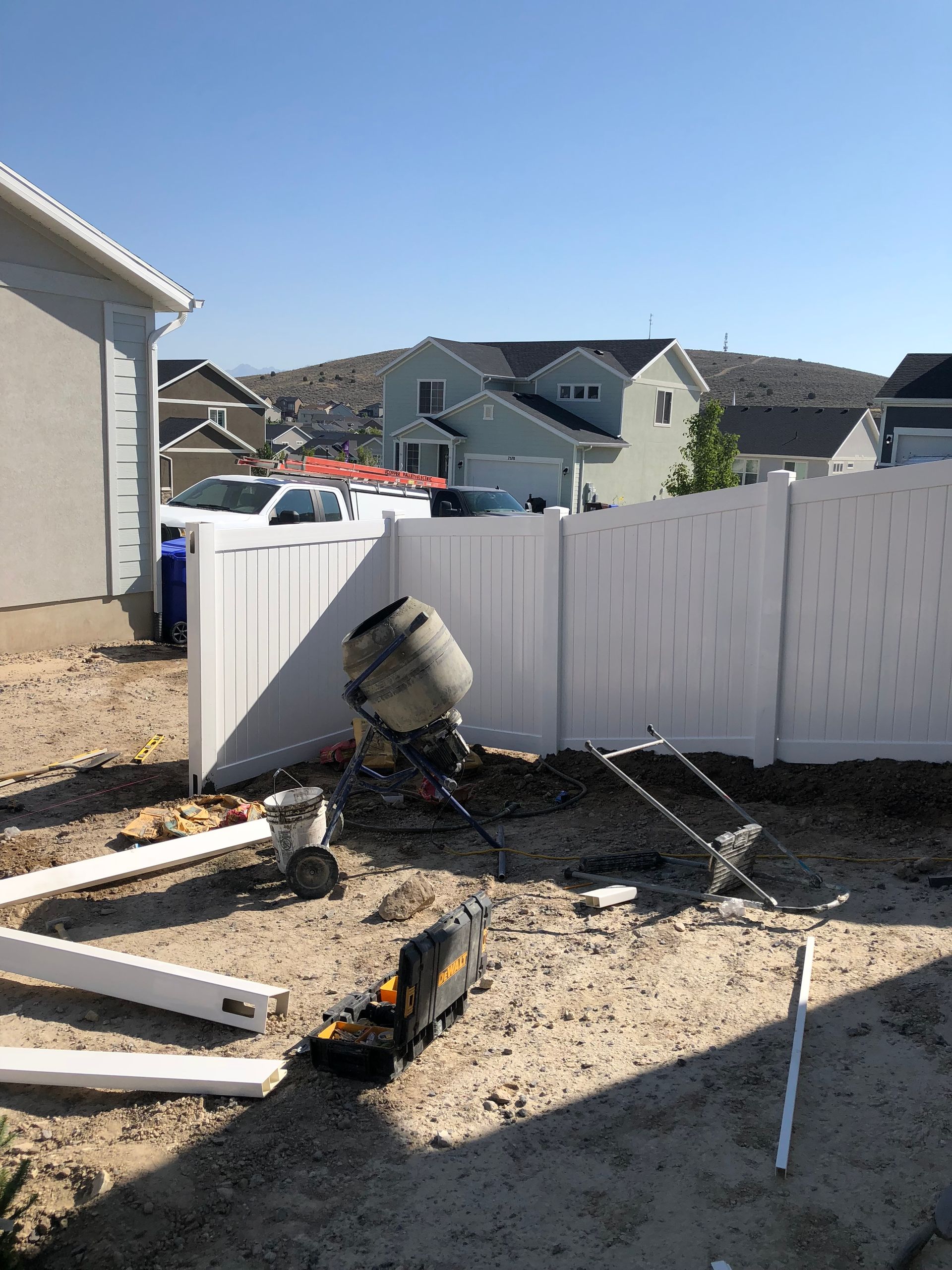 A white fence is being built in the backyard of a house.