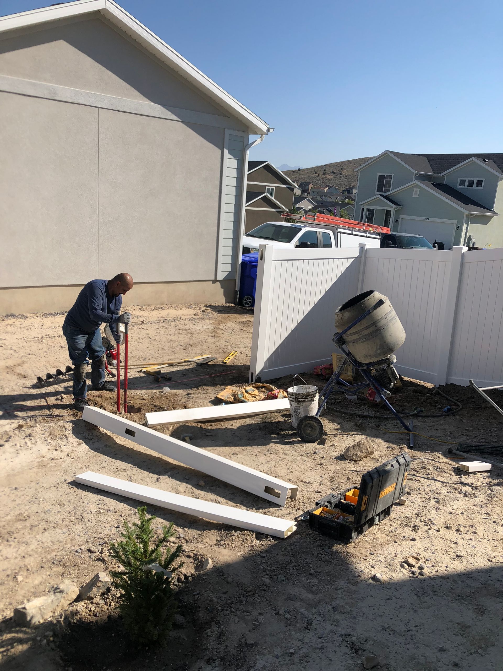 A man is working on a fence in front of a house.