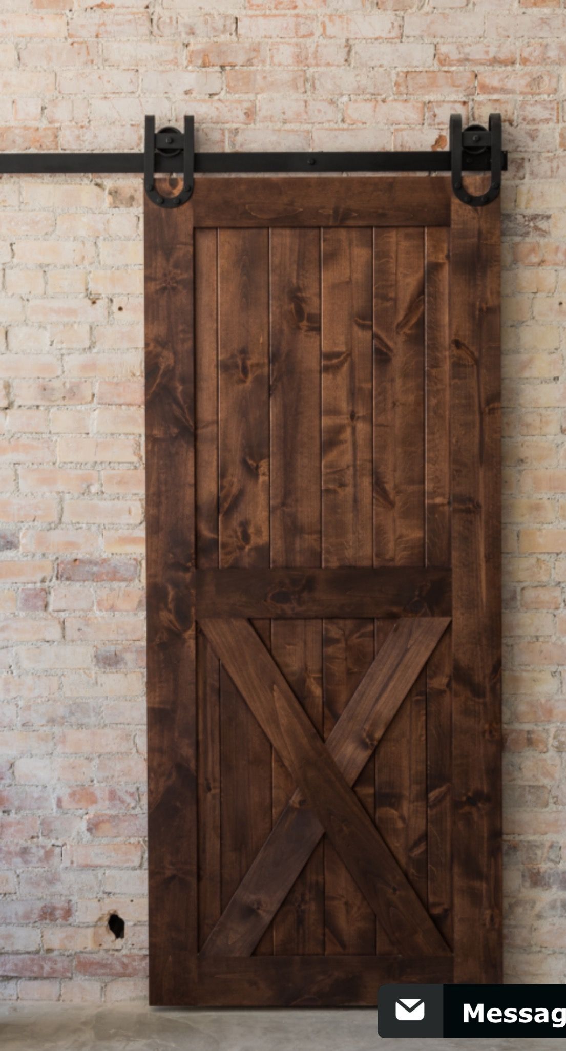 A wooden sliding barn door against a brick wall