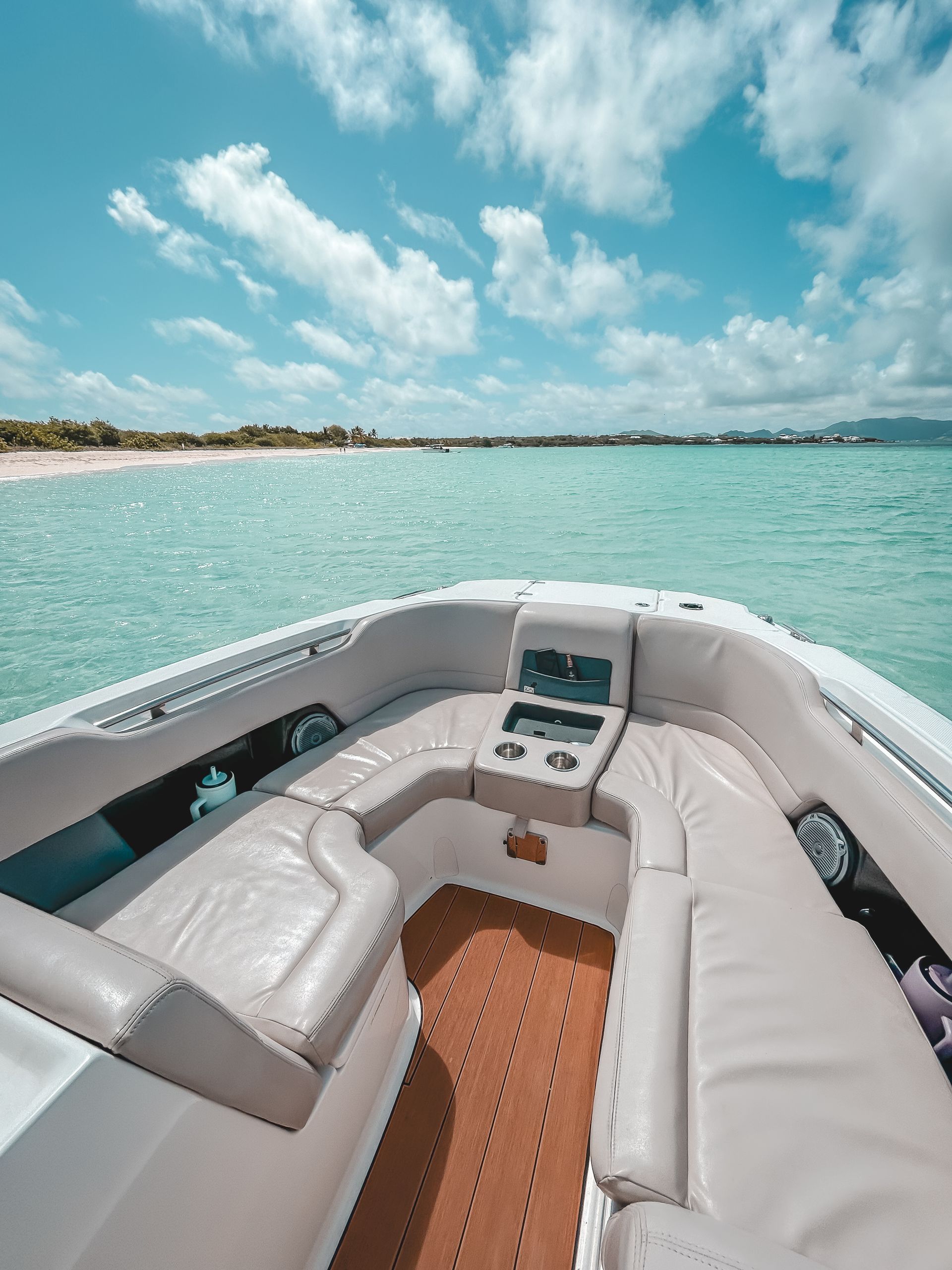 Boat interior overlooking turquoise water and beach under a blue sky.