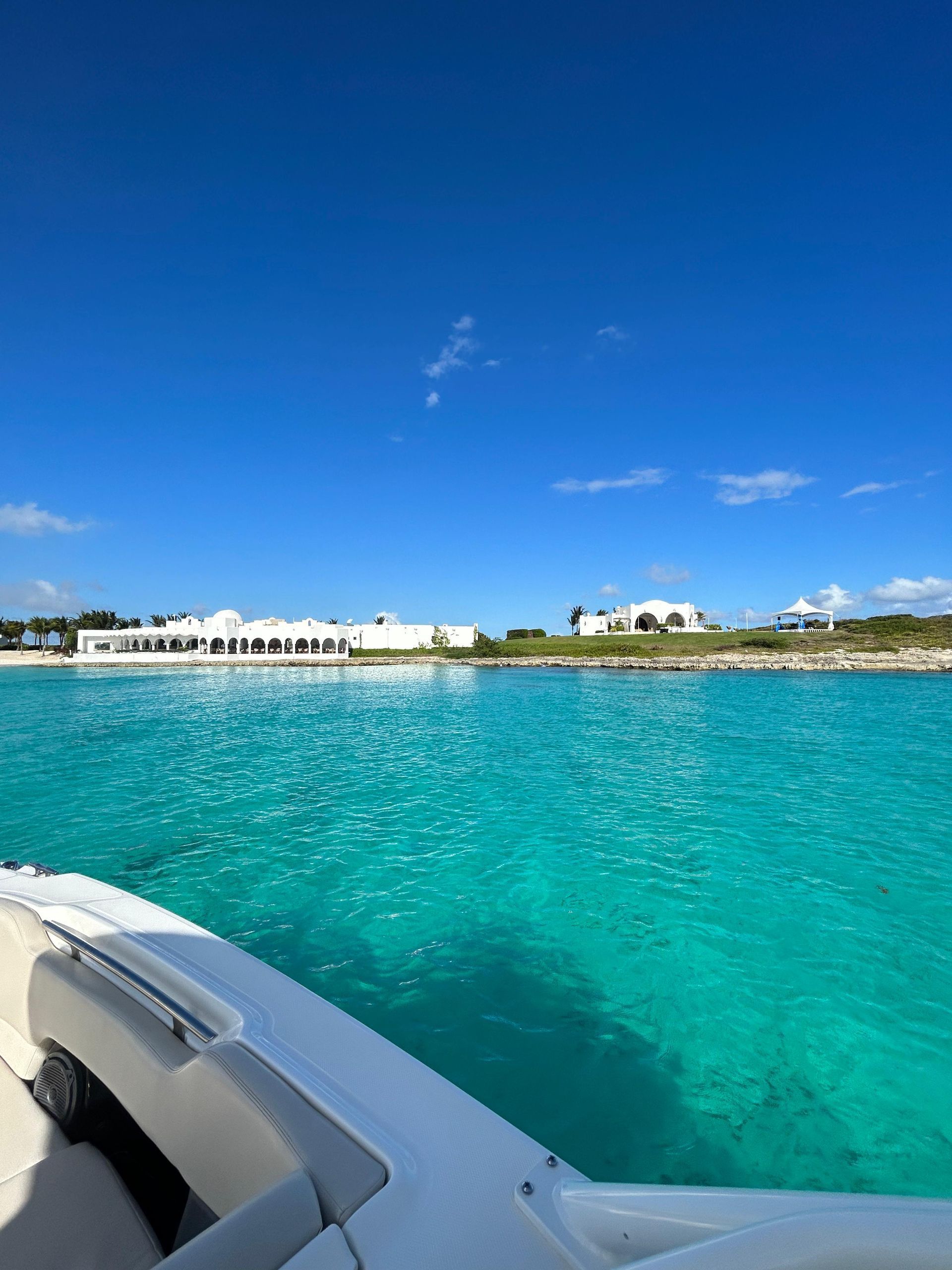 Bright turquoise water with white boat and buildings against a vibrant blue sky.
