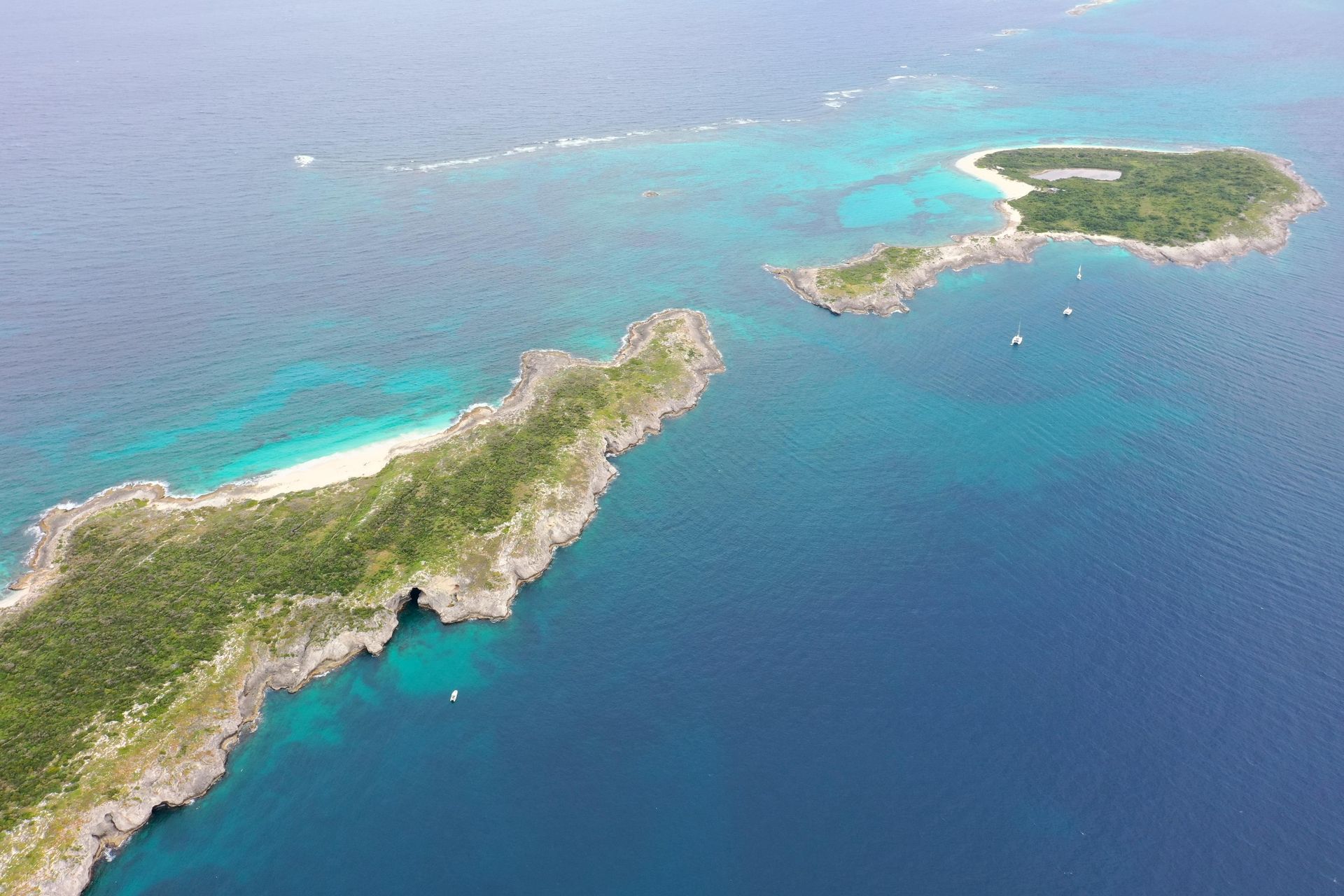 Aerial view of small islands with turquoise and deep blue water. Green vegetation and sandy beaches.