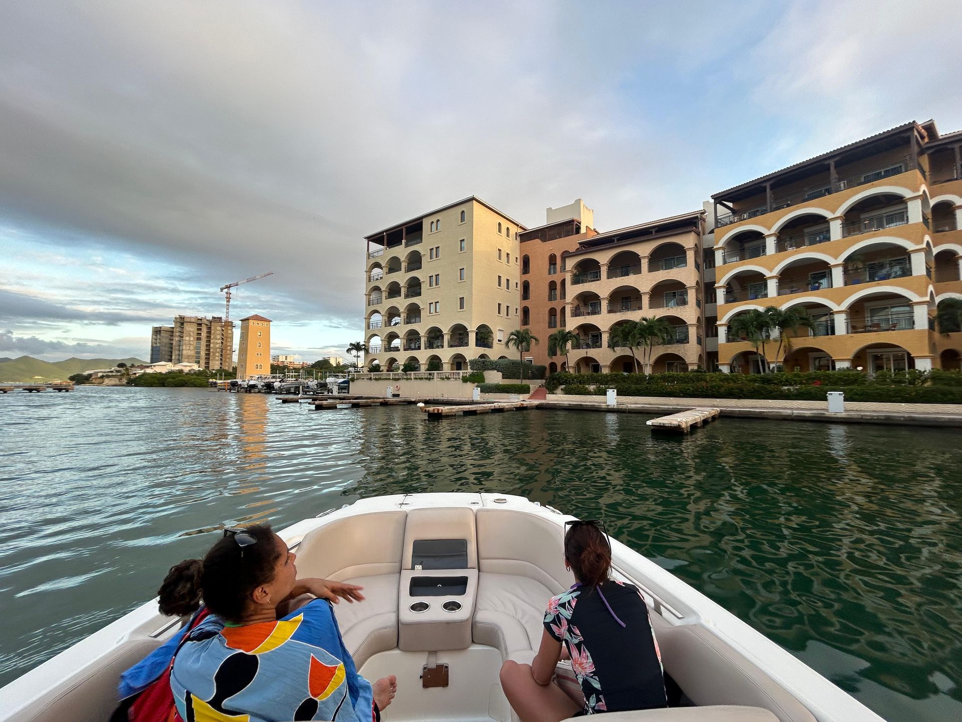 People on a boat near buildings with arched windows in an overcast day.