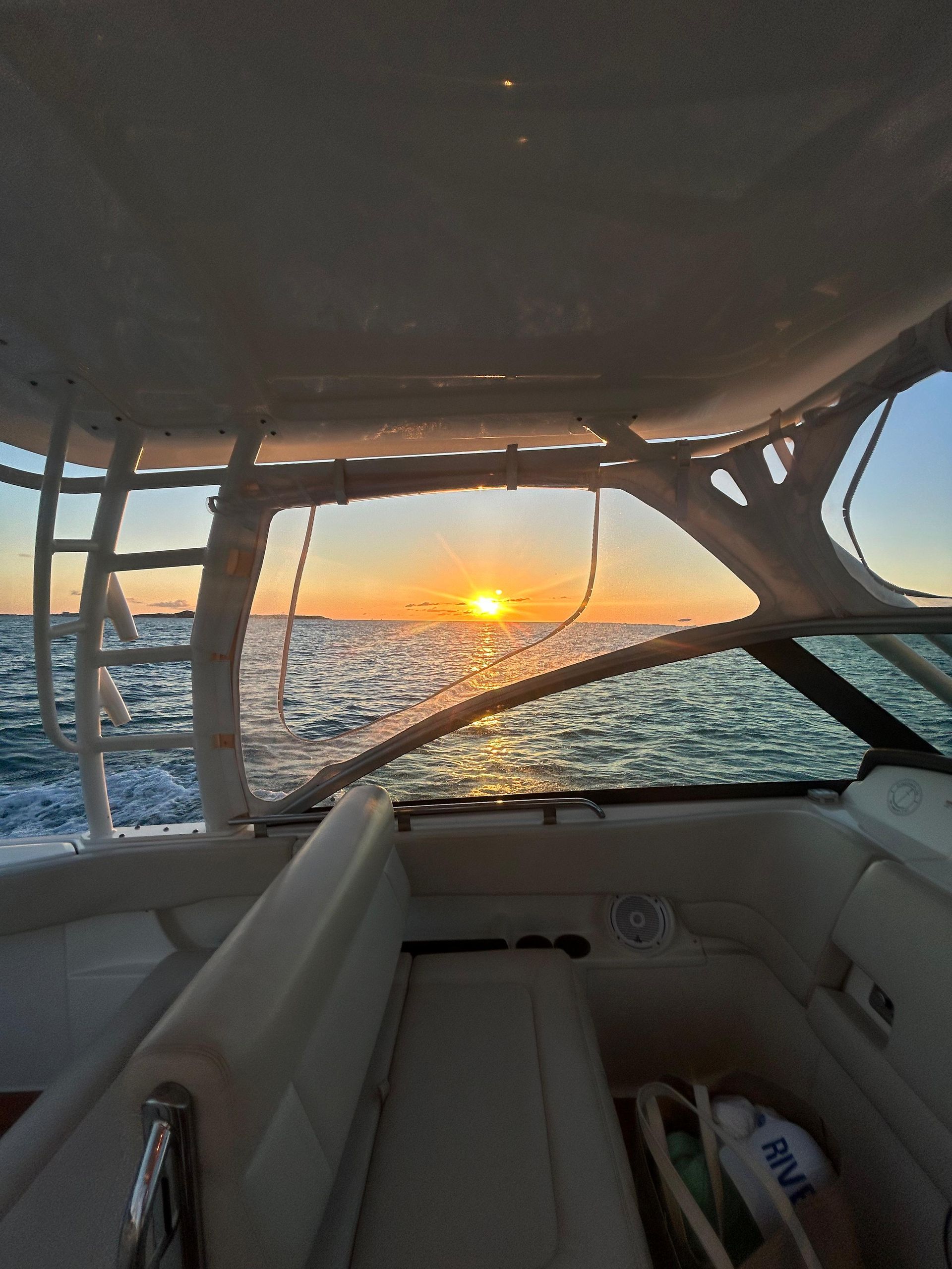 Sunset seen through the windshield of a boat on the water.