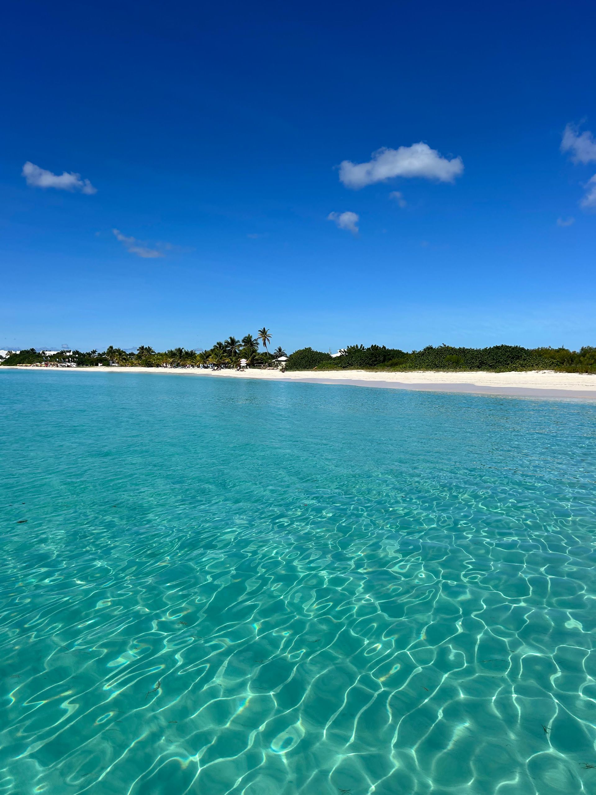 Turquoise water meets white sand beach under a bright blue sky.
