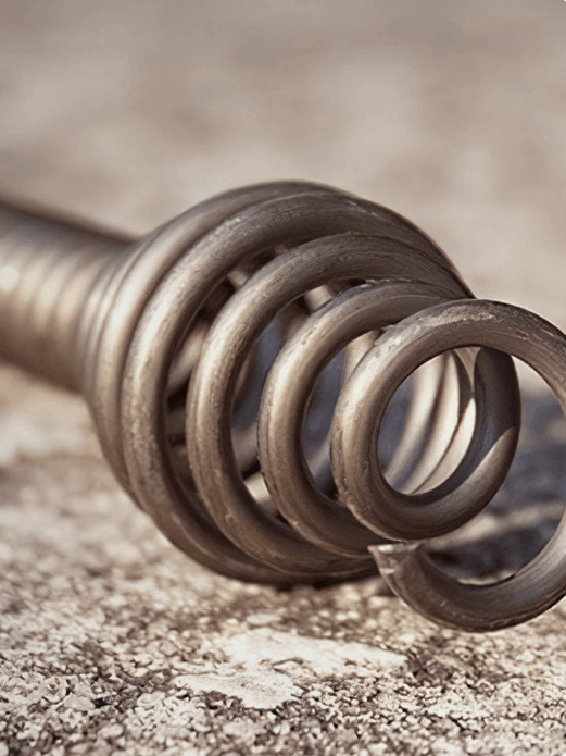 A close up of a metal spring on a concrete surface