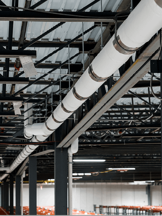 A warehouse with a lot of pipes hanging from the ceiling