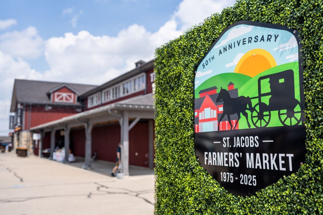 St. Jacobs Farmers’ Market sign beside a red market building on a sunny day