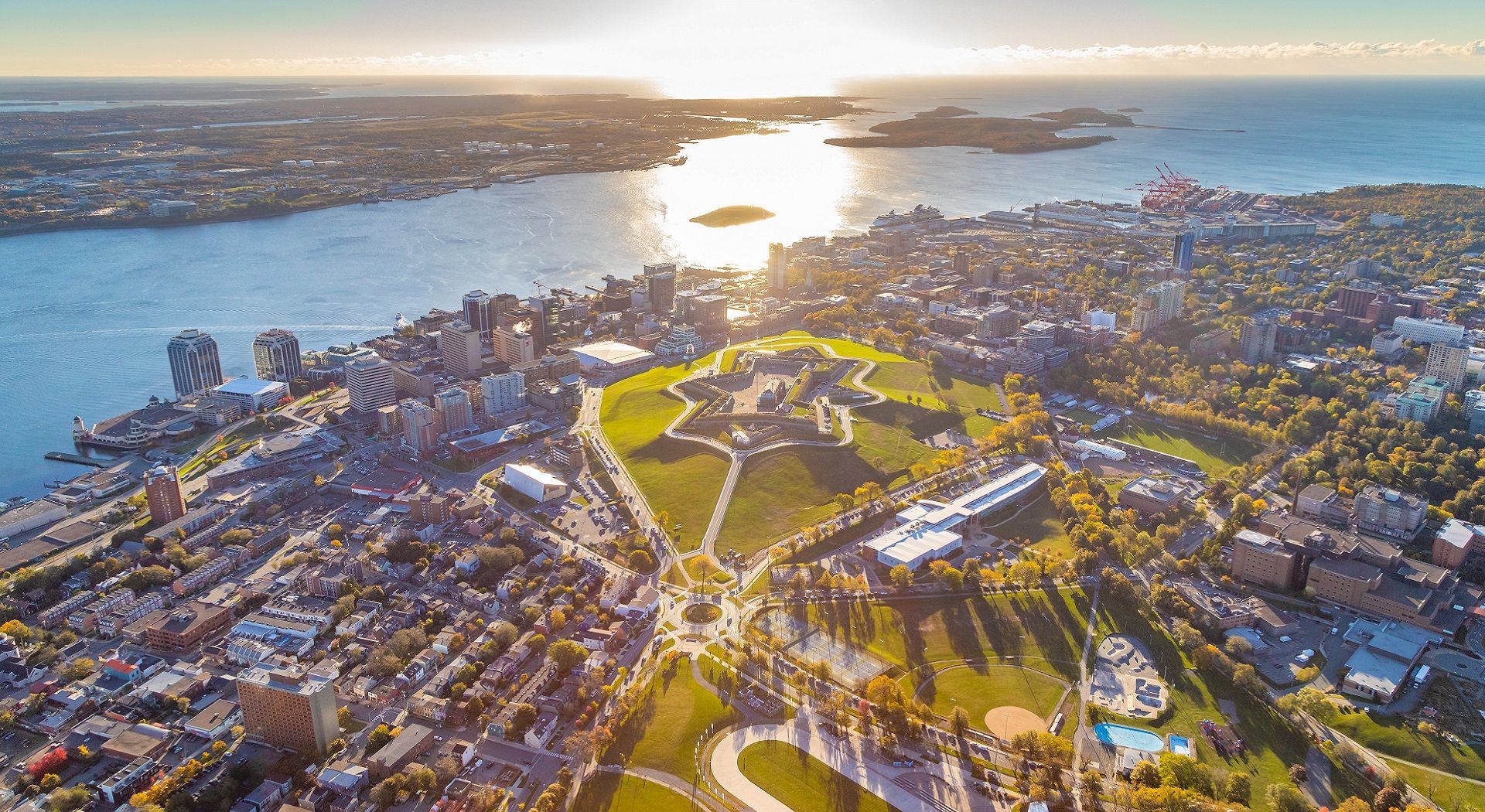 Aerial view of Halifax, Nova Scotia, with Citadel Hill in the center, harbor, and buildings, bathed in sunlight.
