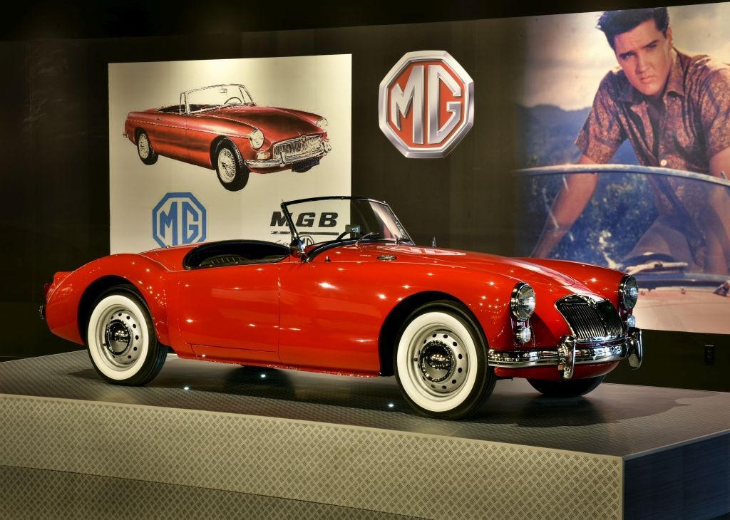 Red MG sports car on display with Elvis Presley image and logo.