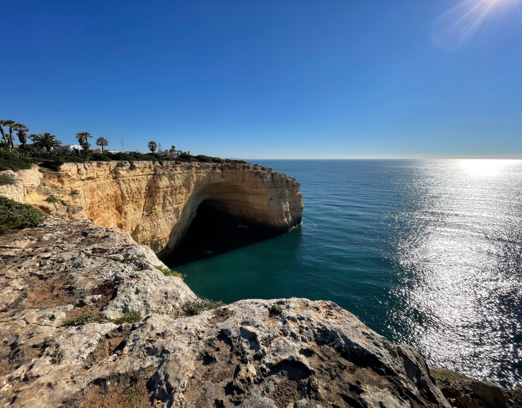 Cliffs overlook turquoise ocean under a bright, sunny sky.