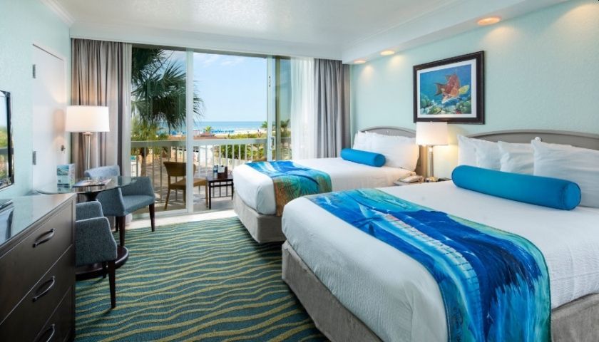 Hotel room with two twin beds, ocean view balcony, and blue decor