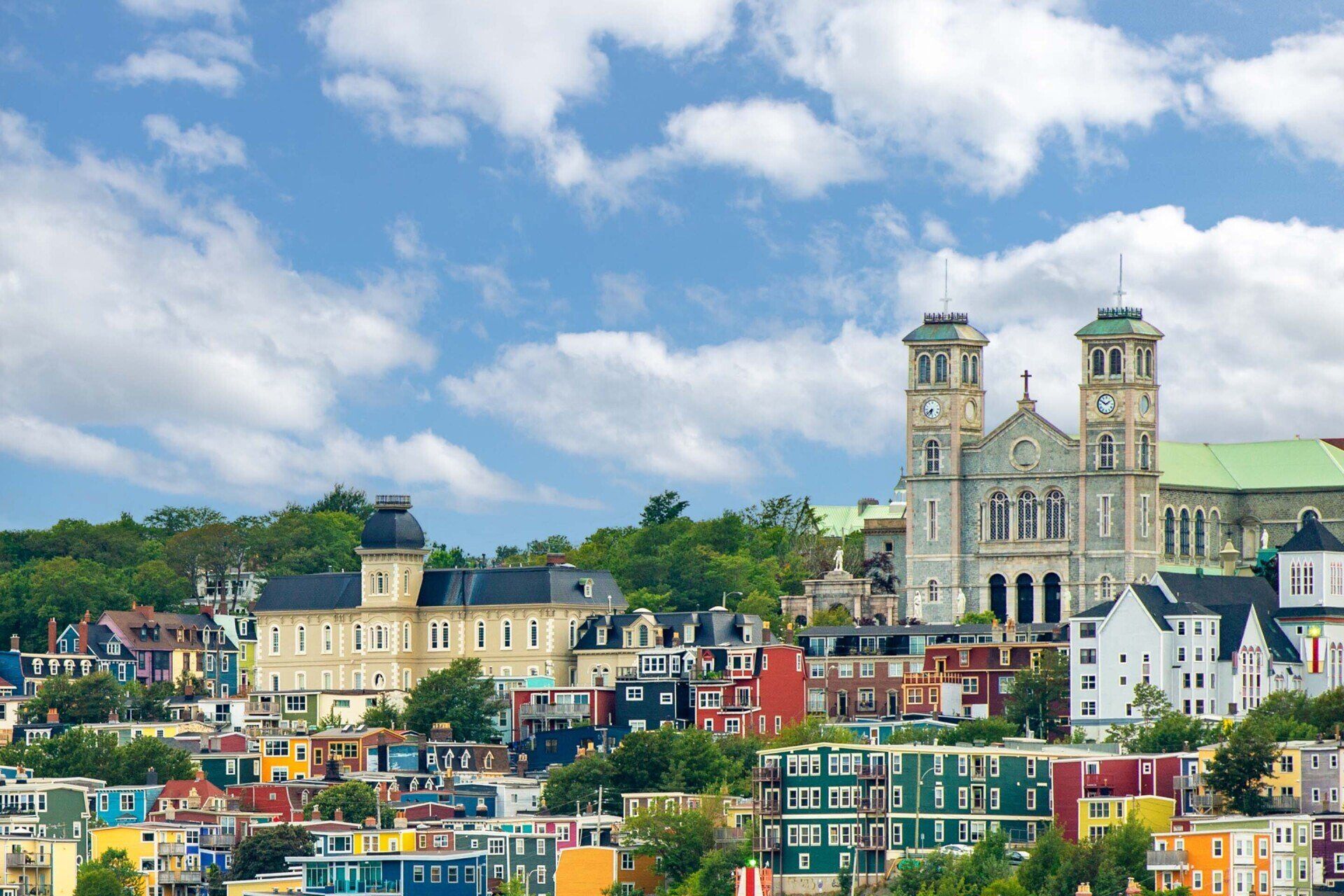 Colorful houses on a hillside in St. John's, Newfoundland, with a large church and blue sky.