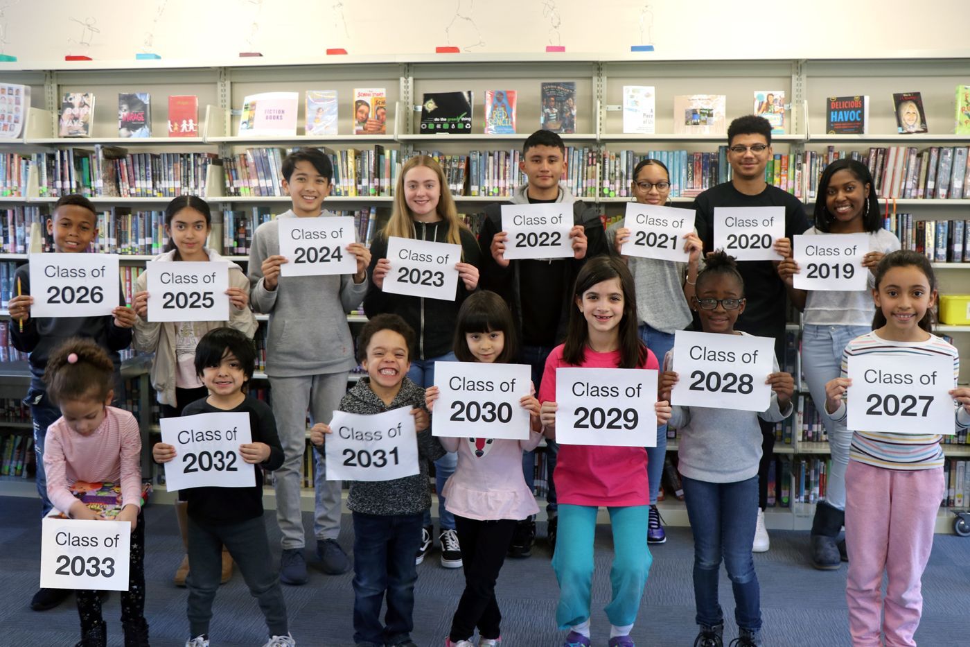 Students holding signs with their class of year on them.