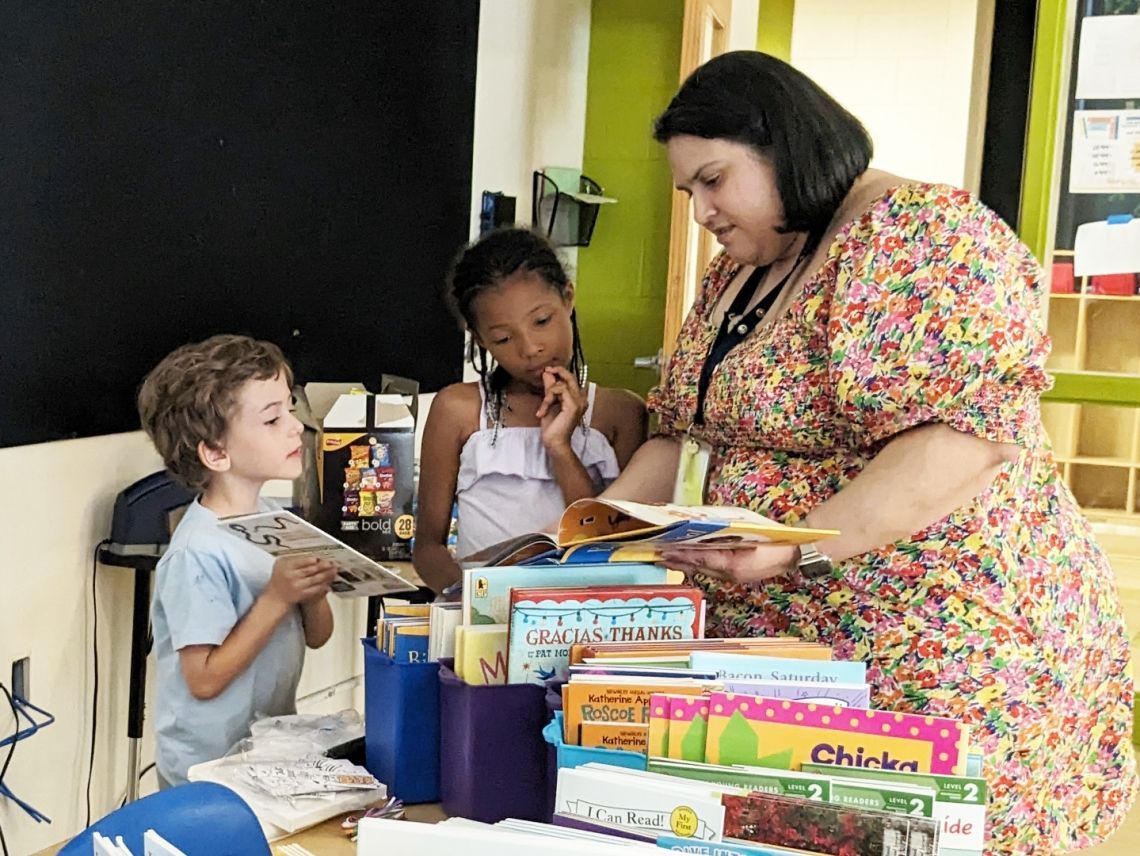 a woman in a colorful dress is reading a book to two children