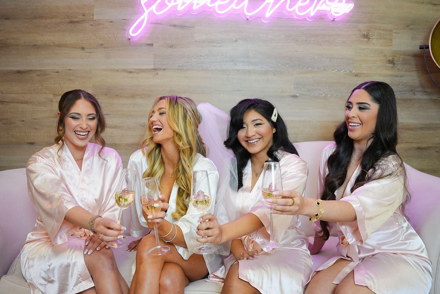 A group of women are sitting on a couch holding champagne glasses.