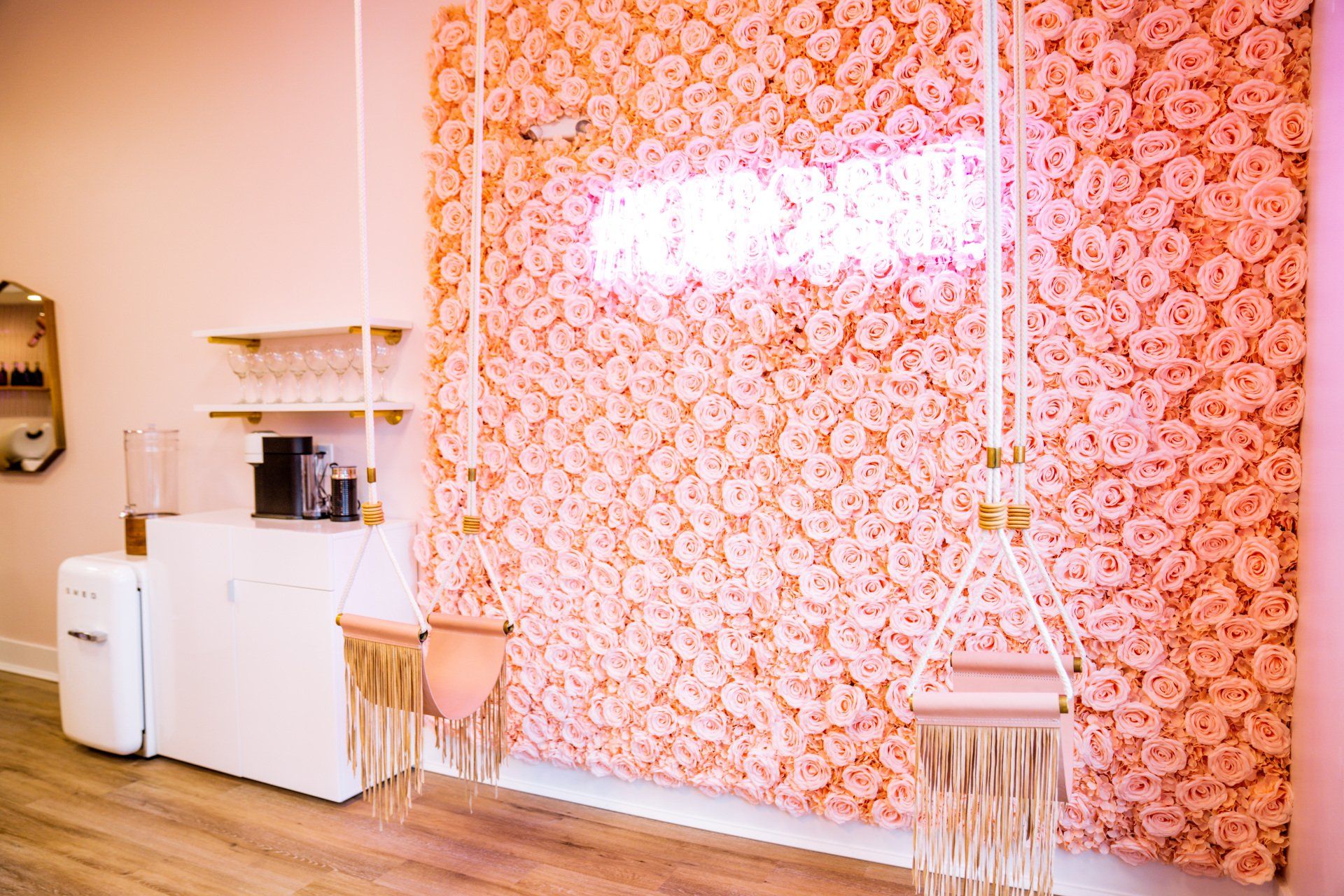 A pink room with a pink flower wall and a pink swing.