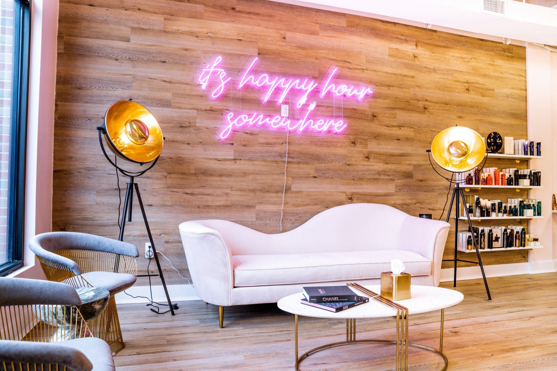 A living room with a couch , table , chairs and a neon sign on the wall.