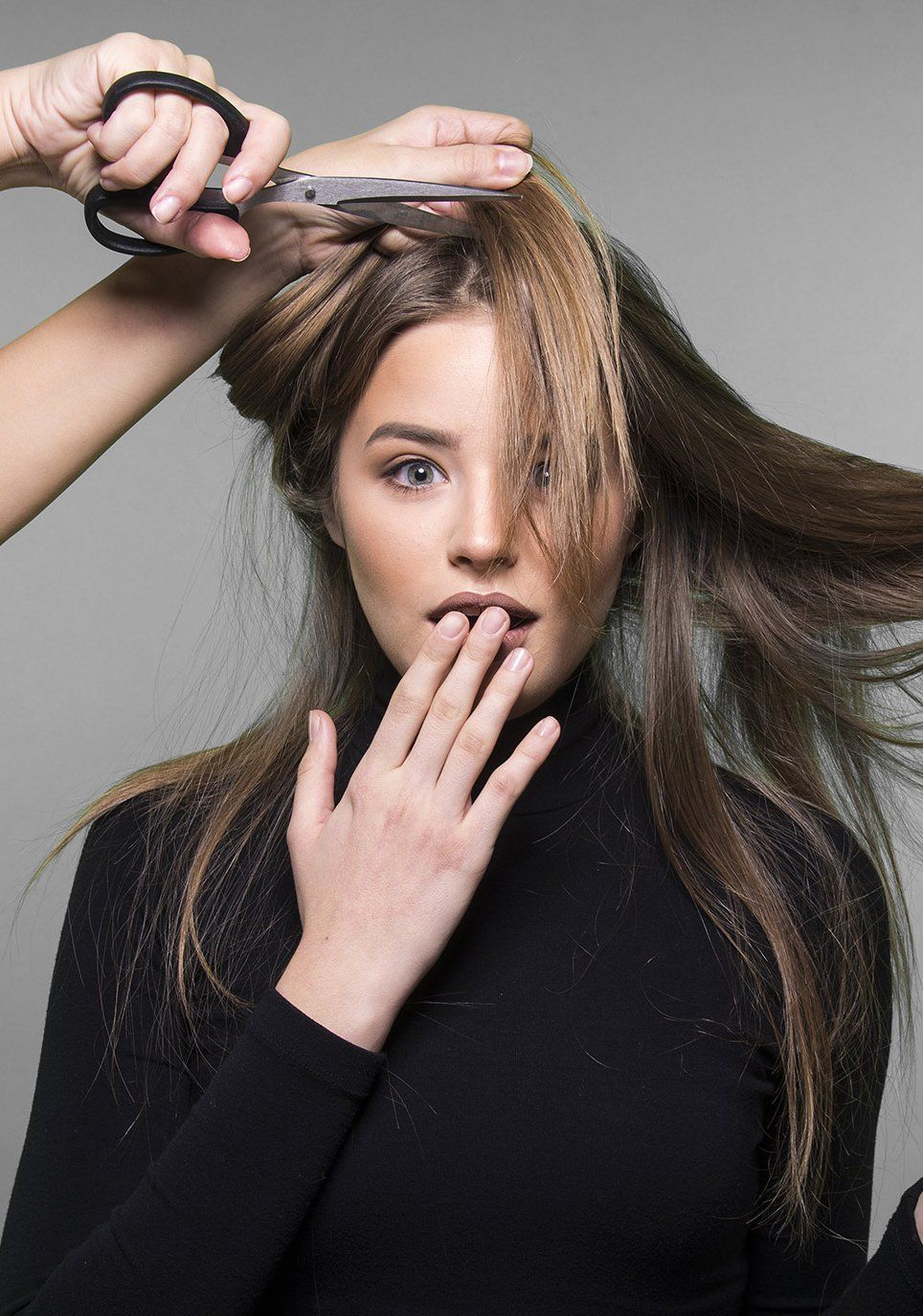 A woman is getting her hair cut by a hairdresser.
