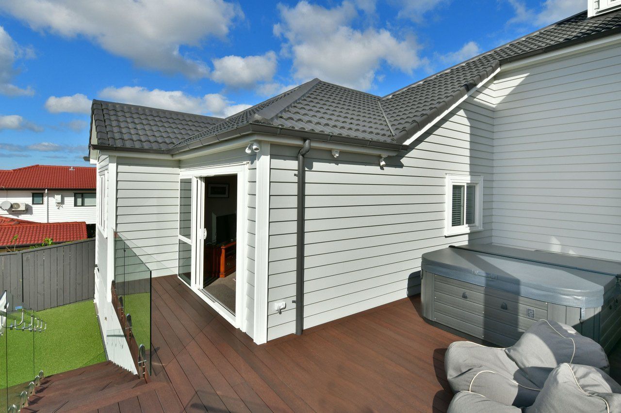 A white house with a wooden deck and a hot tub in the backyard.