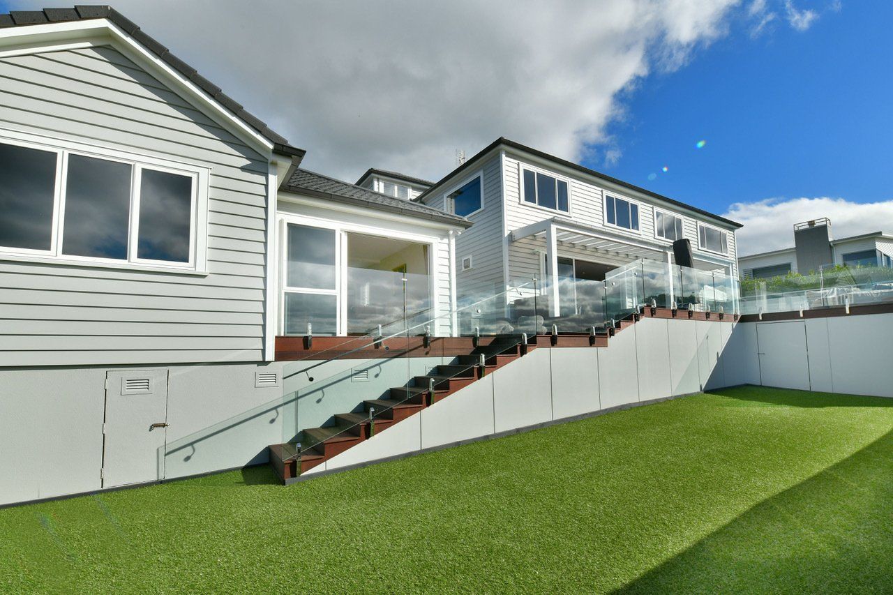 A house with stairs leading up to it and a lawn in front of it.