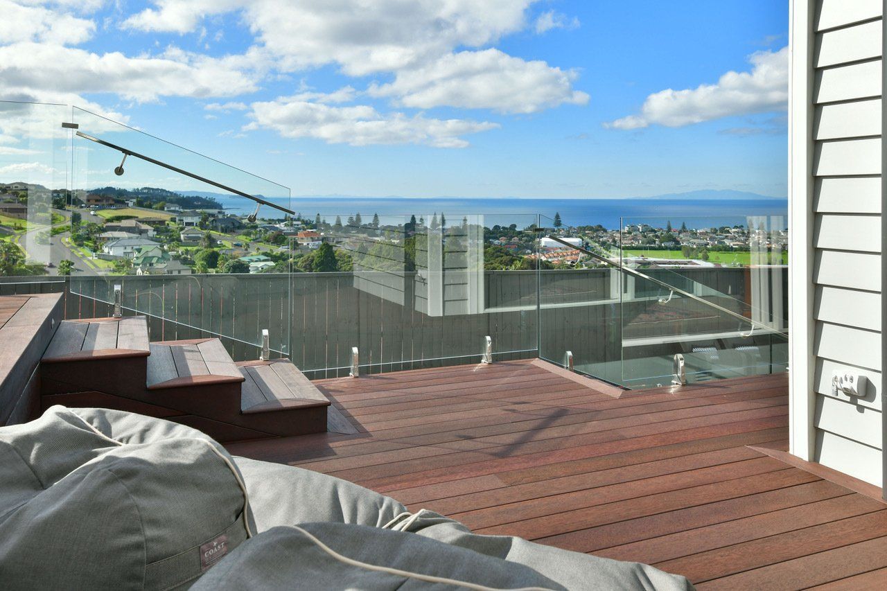 A view of the ocean from a deck with a glass railing