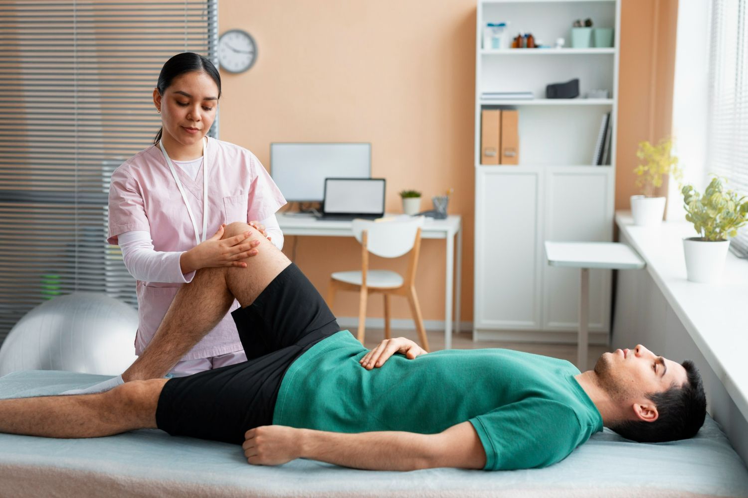 A man is laying on a bed while a nurse stretches his leg.