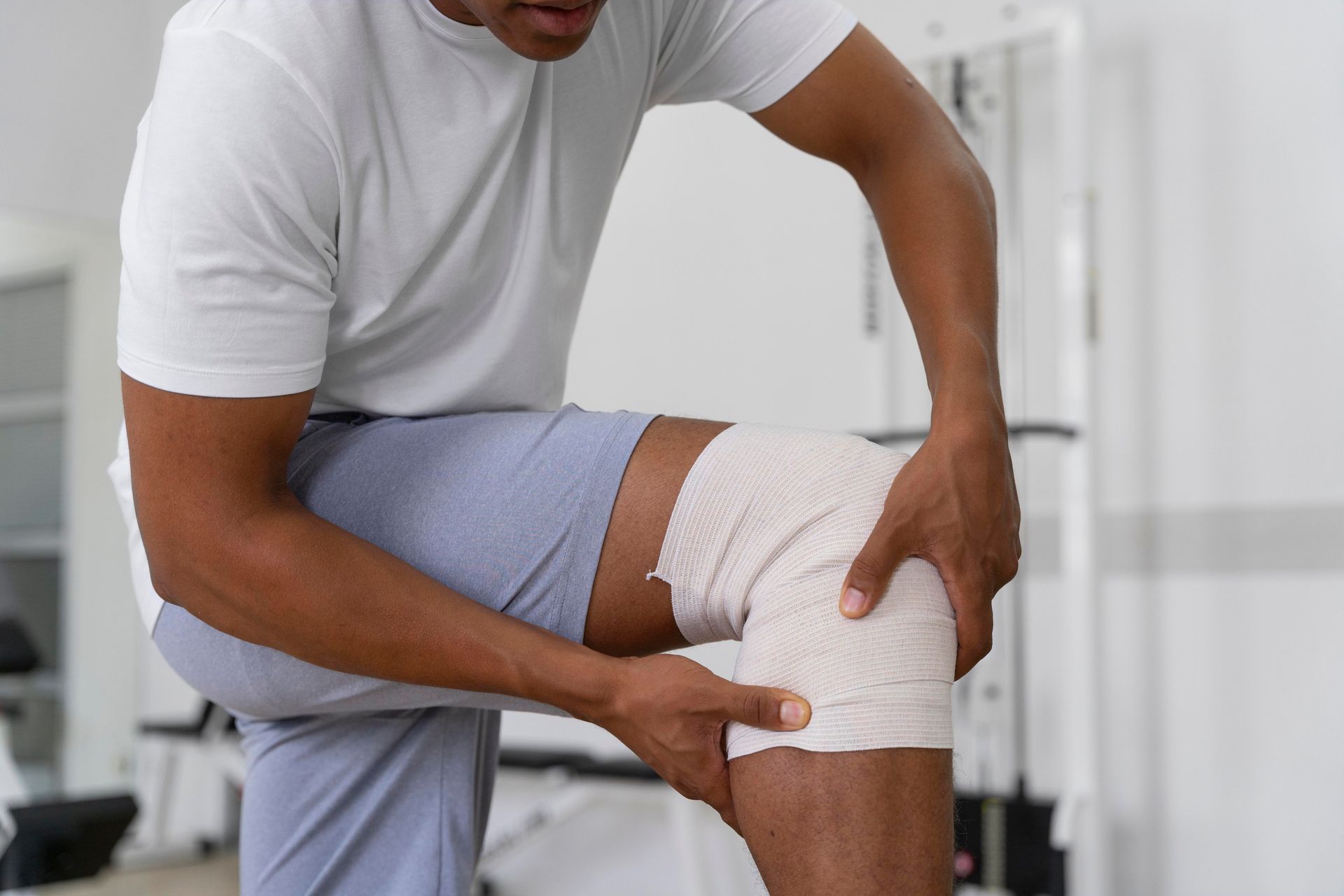 A man is kneeling down with a bandage on his knee.